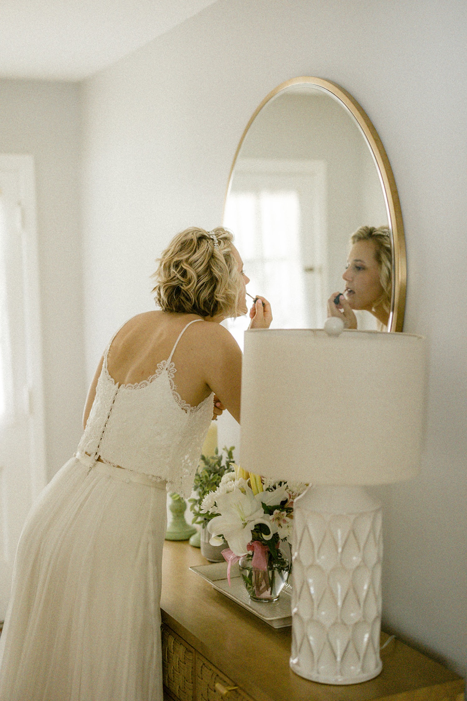 bride putting on lipgloss in the mirror wedding