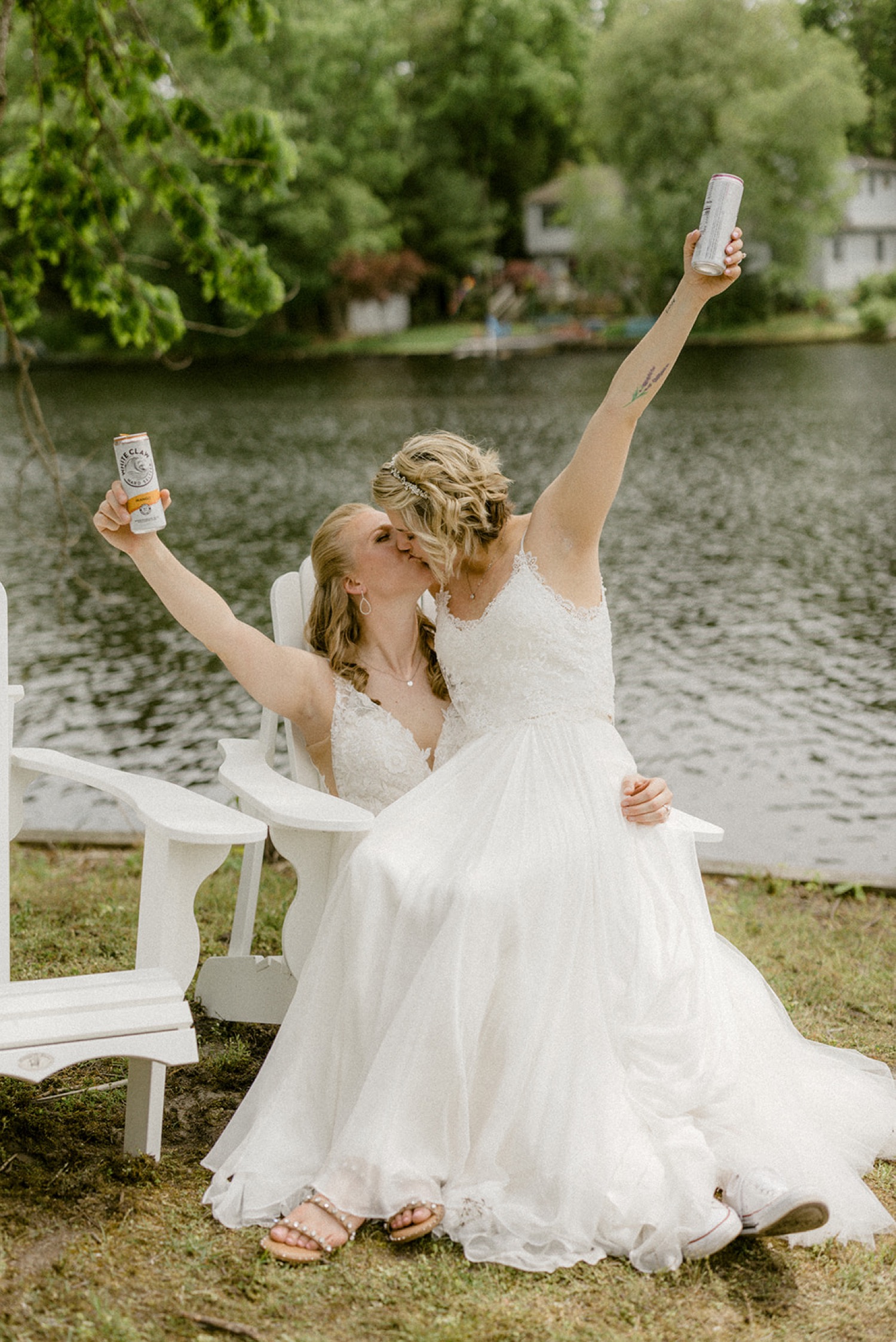 brides kissing holding hard seltzer lakeside backyard micro wedding