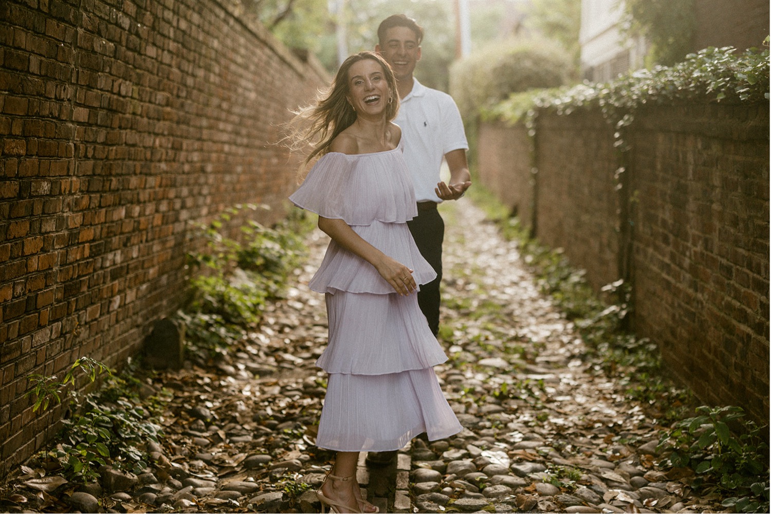 couple running down brick alley engagement session