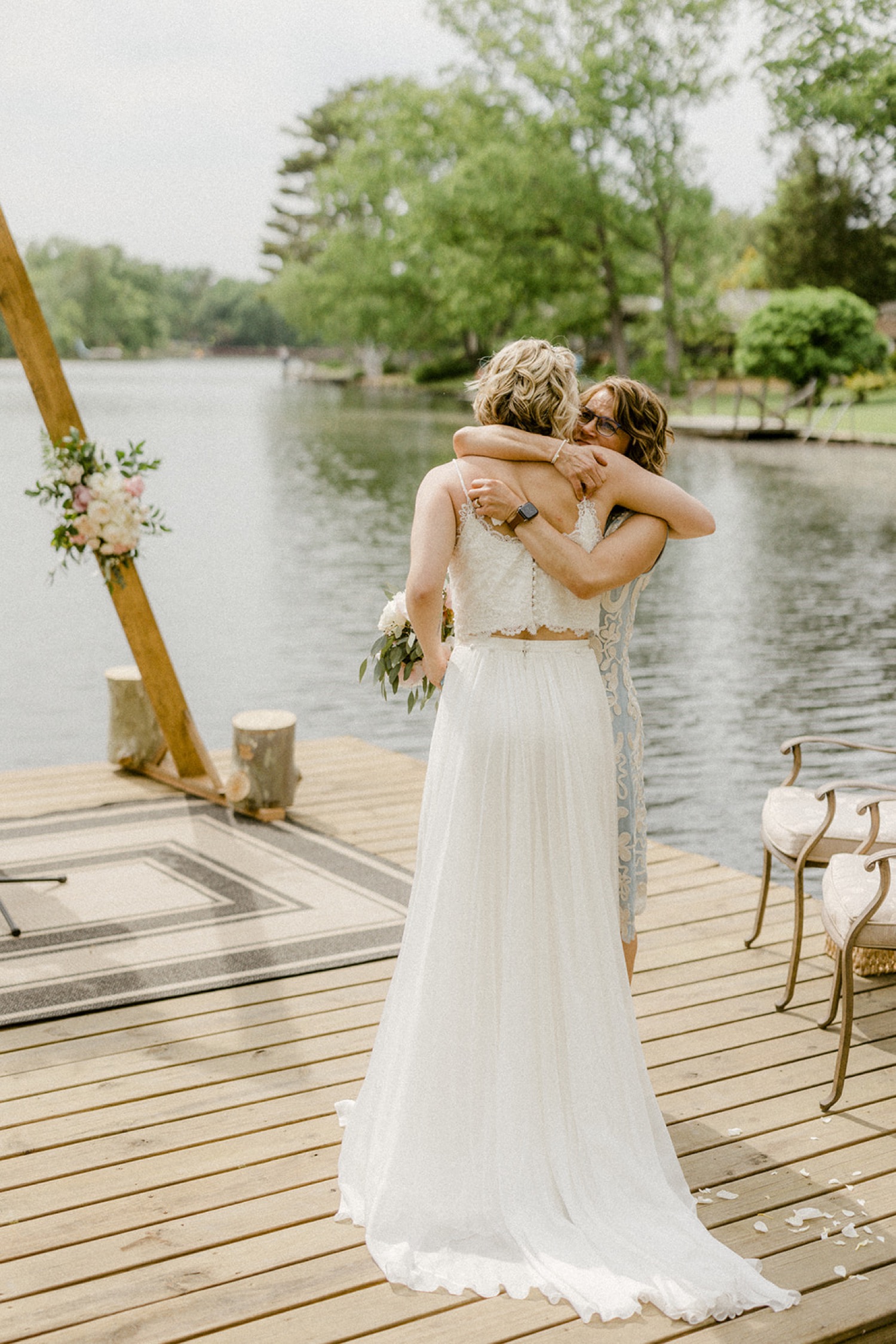bride hugging mom on dock lakeside backyard micro wedding