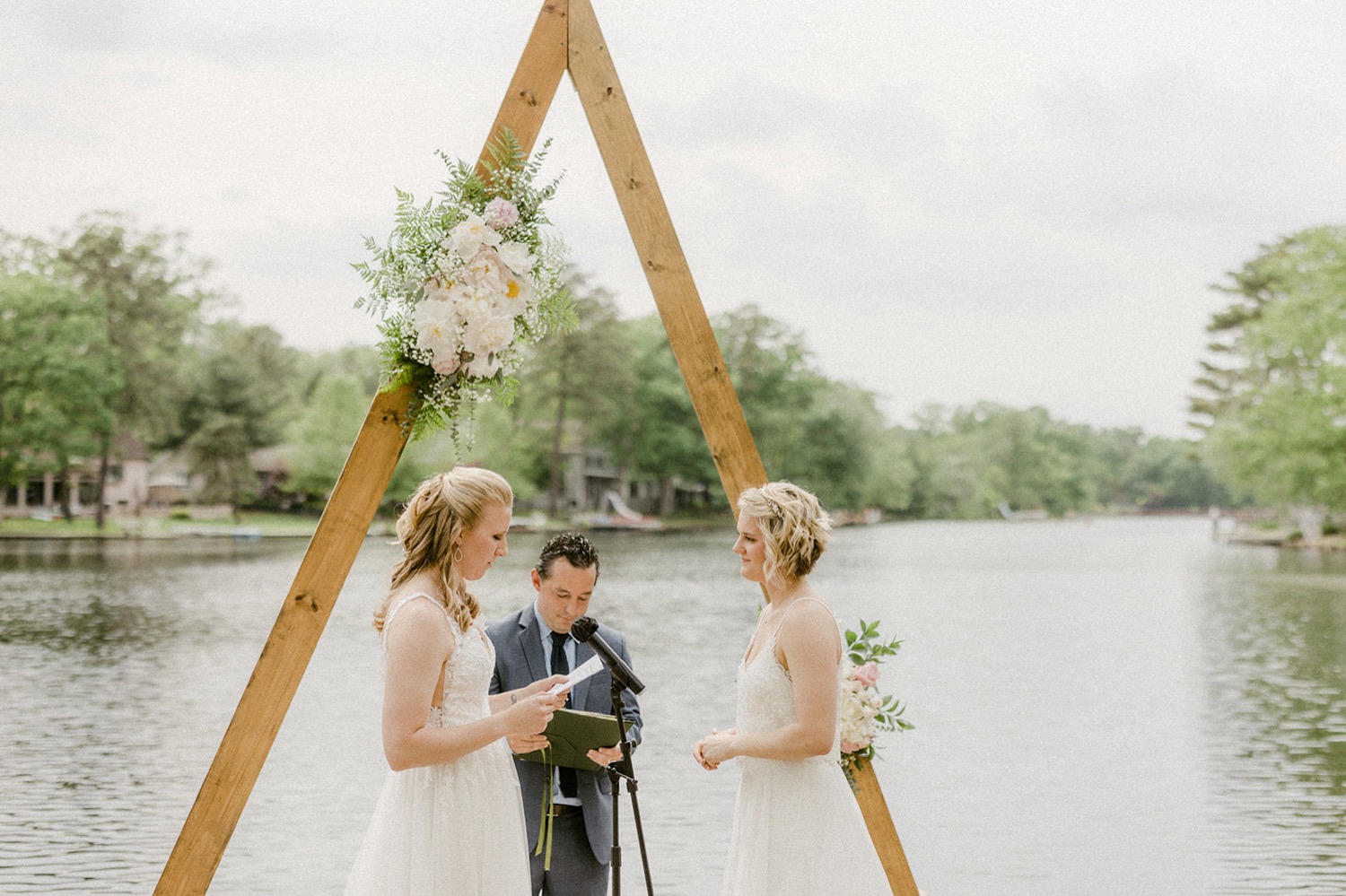 brides reading vows in front of lakeside arbor micro wedding