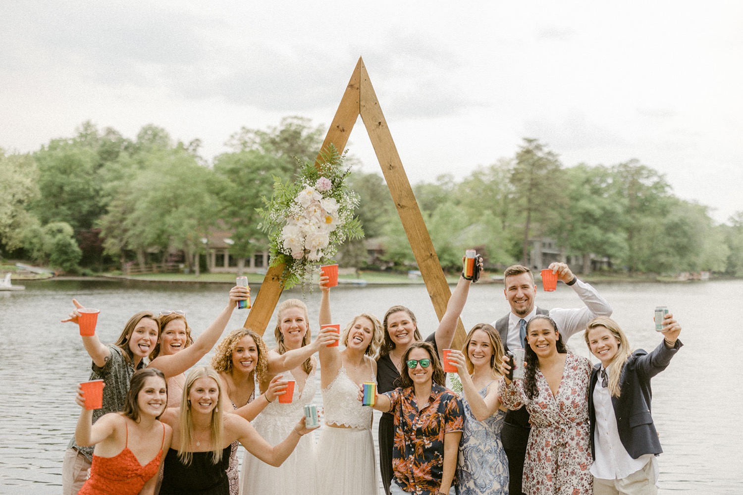 brides and friends raising cups lakeside backyard micro wedding