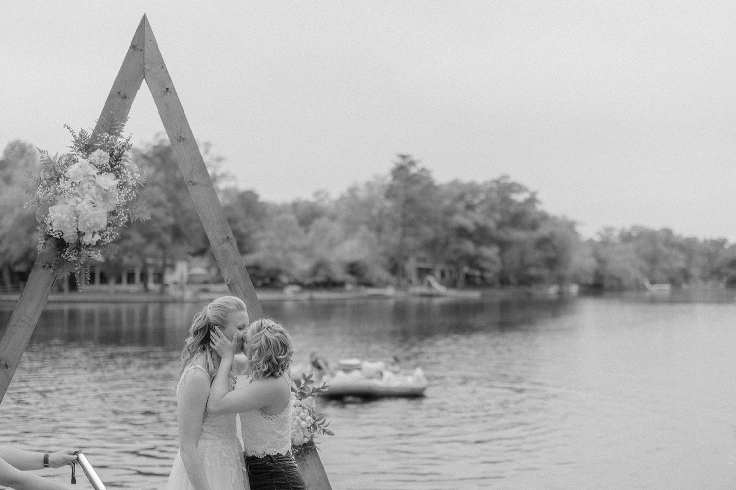 brides kissing in front of arbor lakeside micro wedding