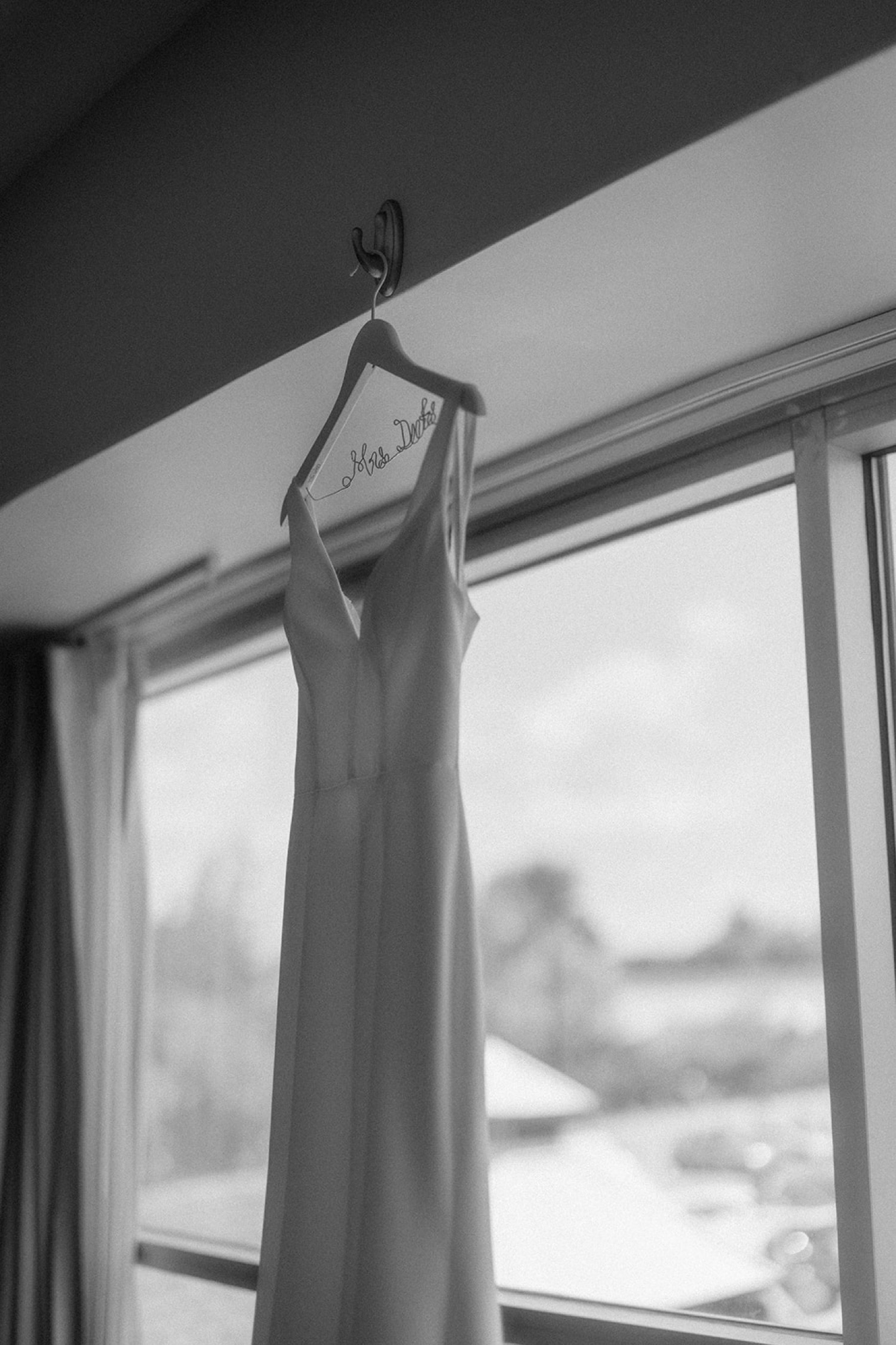 wedding dress on hanger in front of window