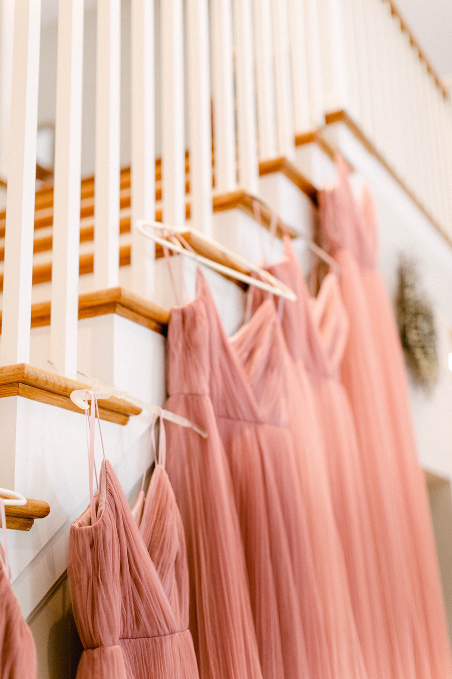 pink bridesmaids dresses hanging on staircase railing