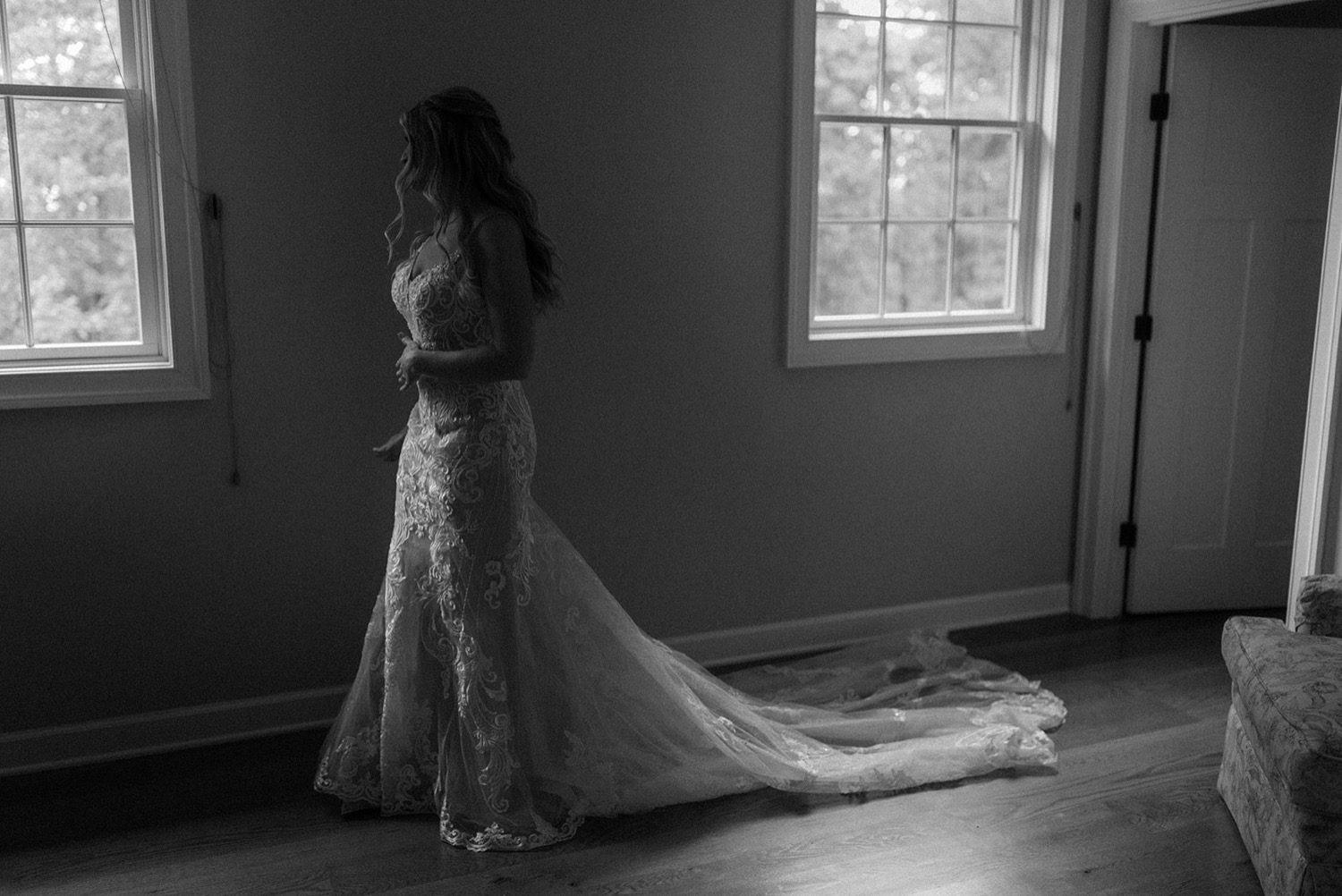 black and white shadowy light bride looking out window in wedding dress