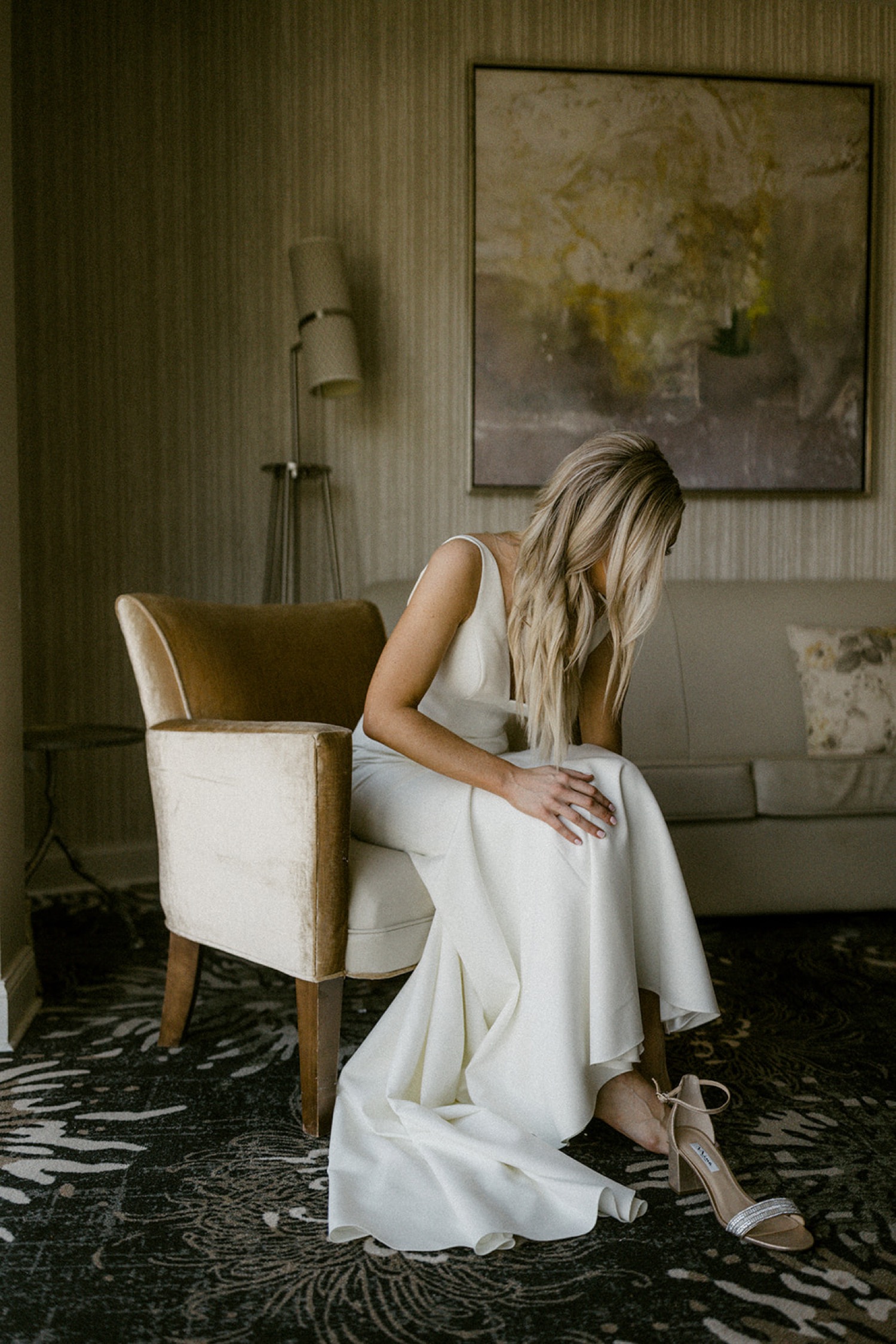 bride putting on wedding shoes sitting in chair