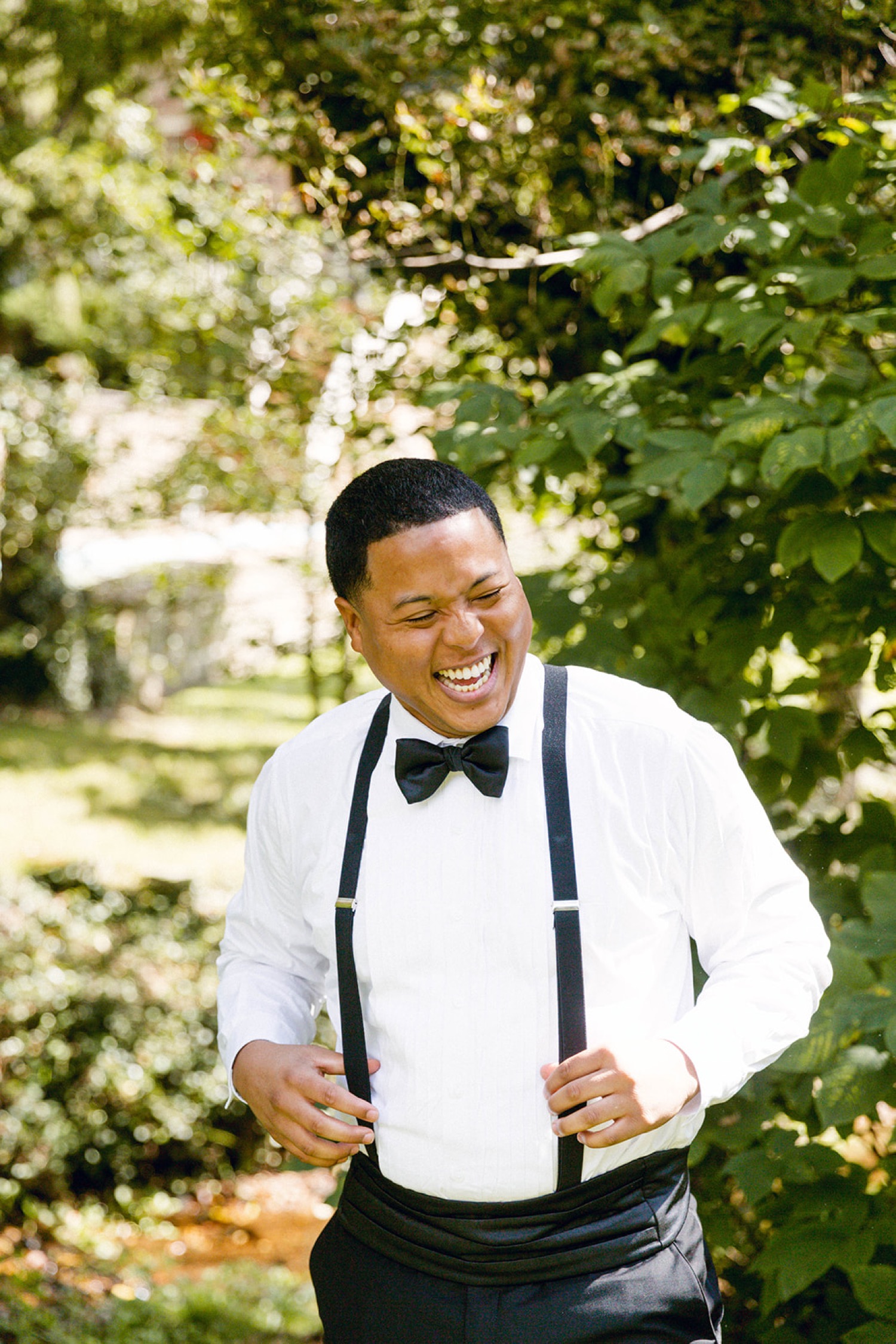groom laughing getting ready for wedding suspenders