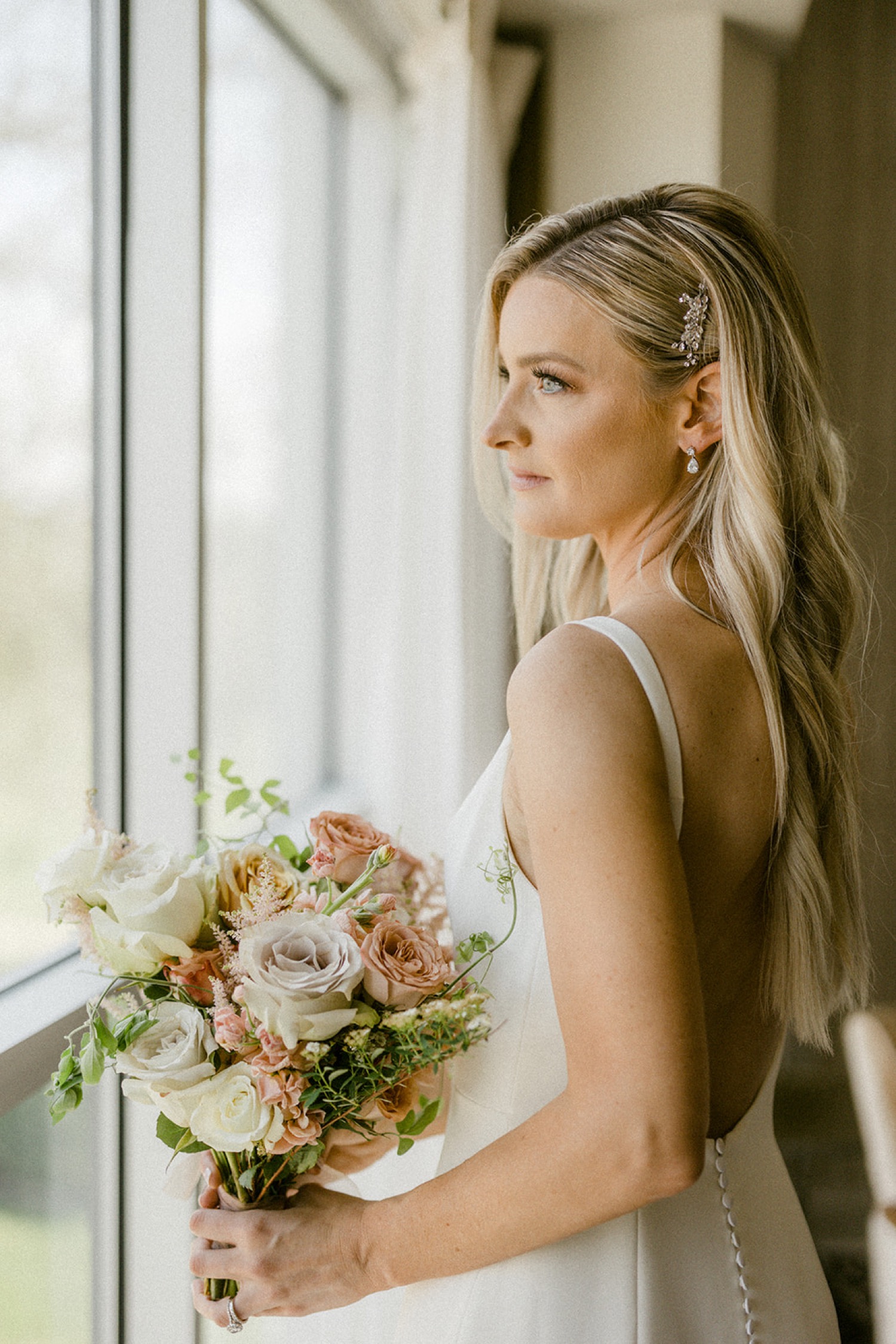 bride holding bouquet looking out window