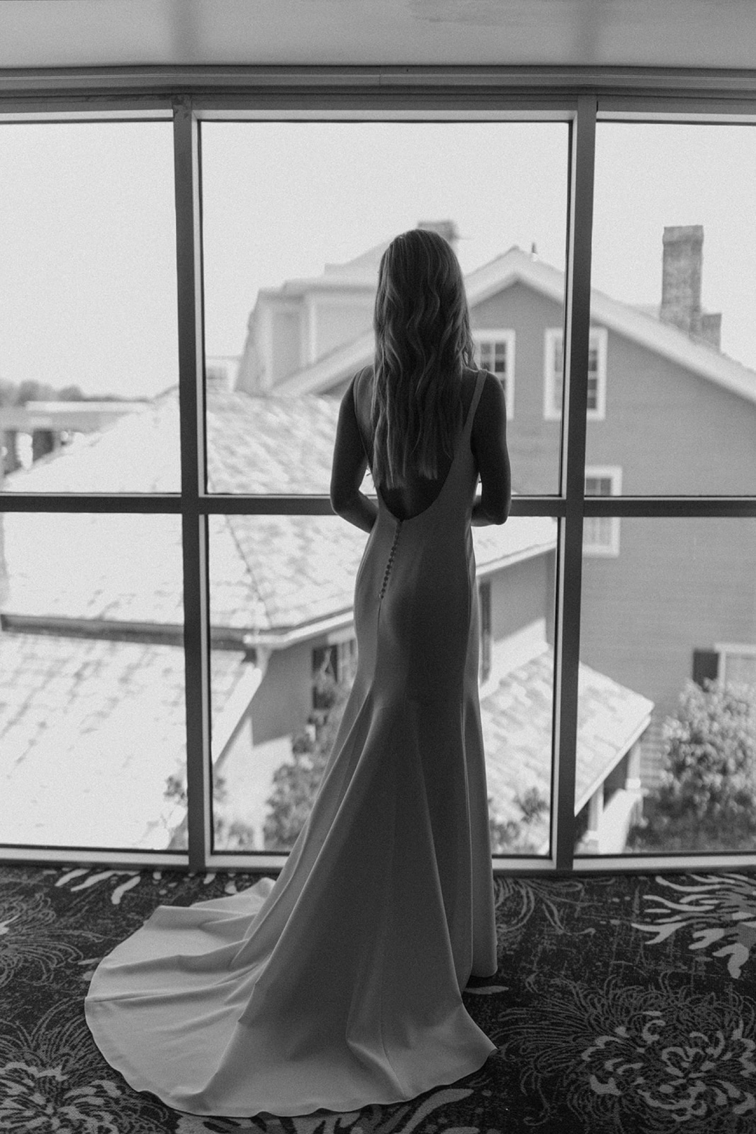 bride looking out large windows in wedding dress