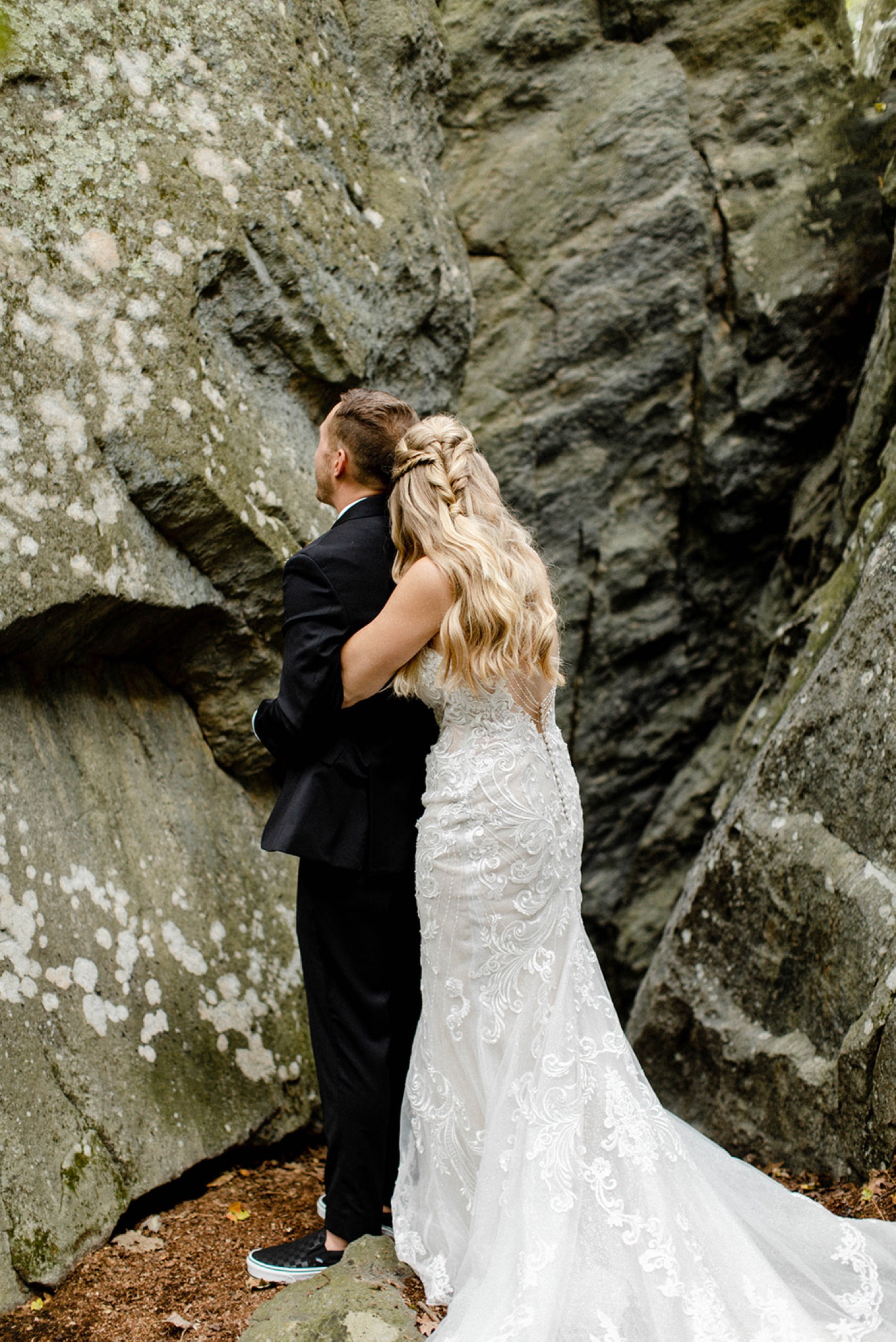 bride hugging groom from behind in rocky outdoor
