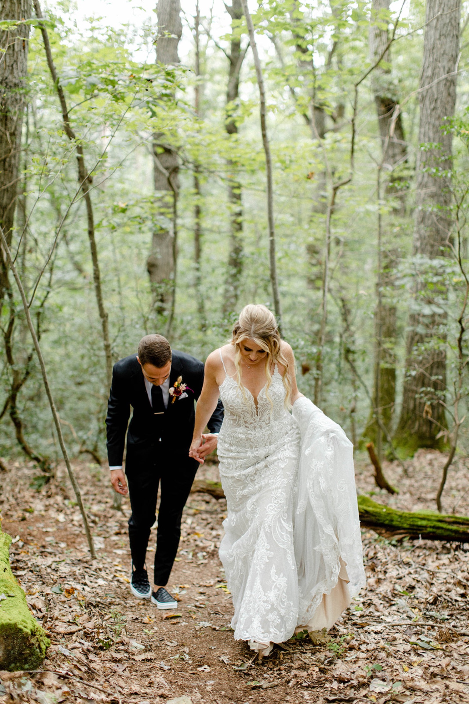 bride and groom walking up hill in forest