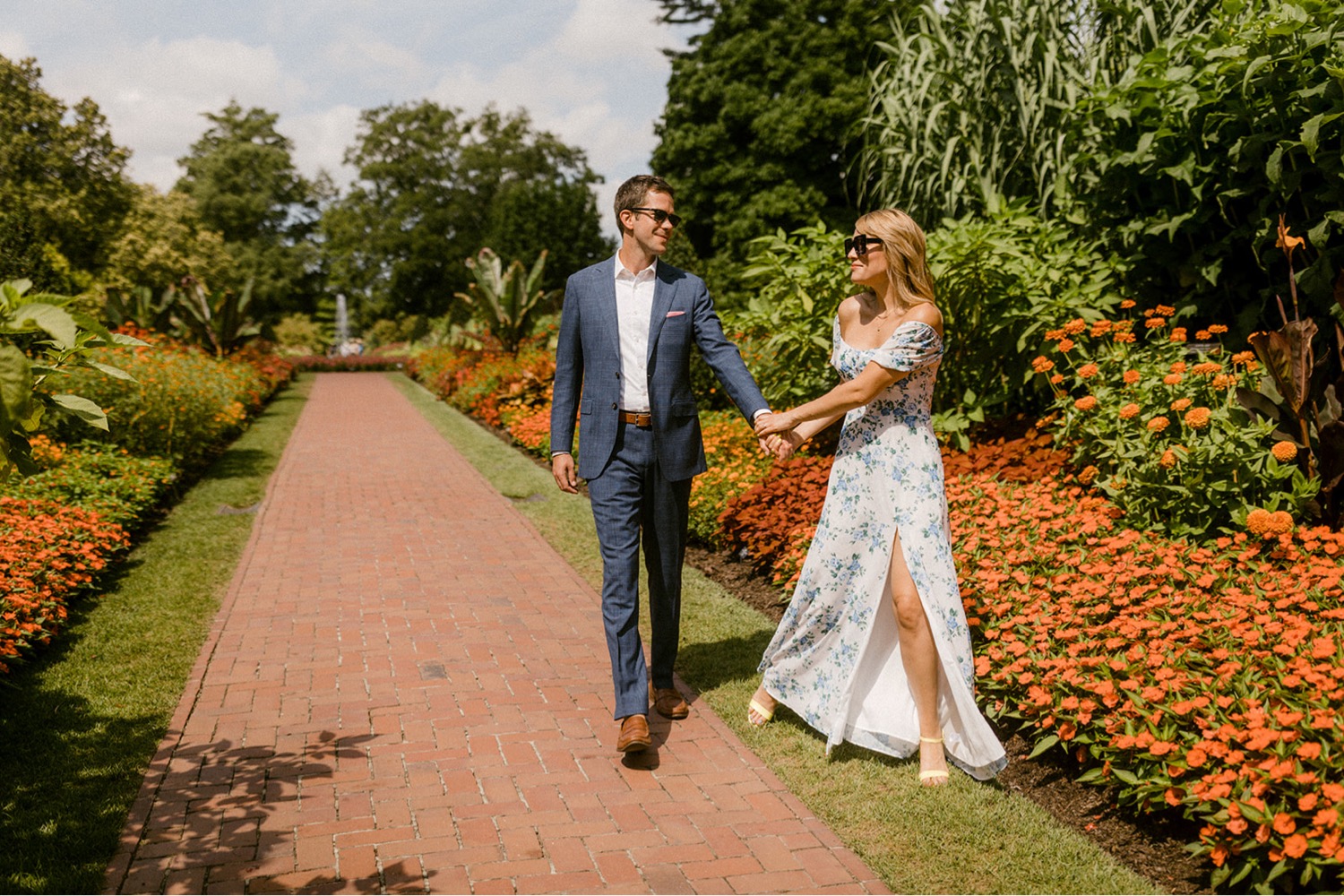longwood gardens couple holding hands walking orange flowers