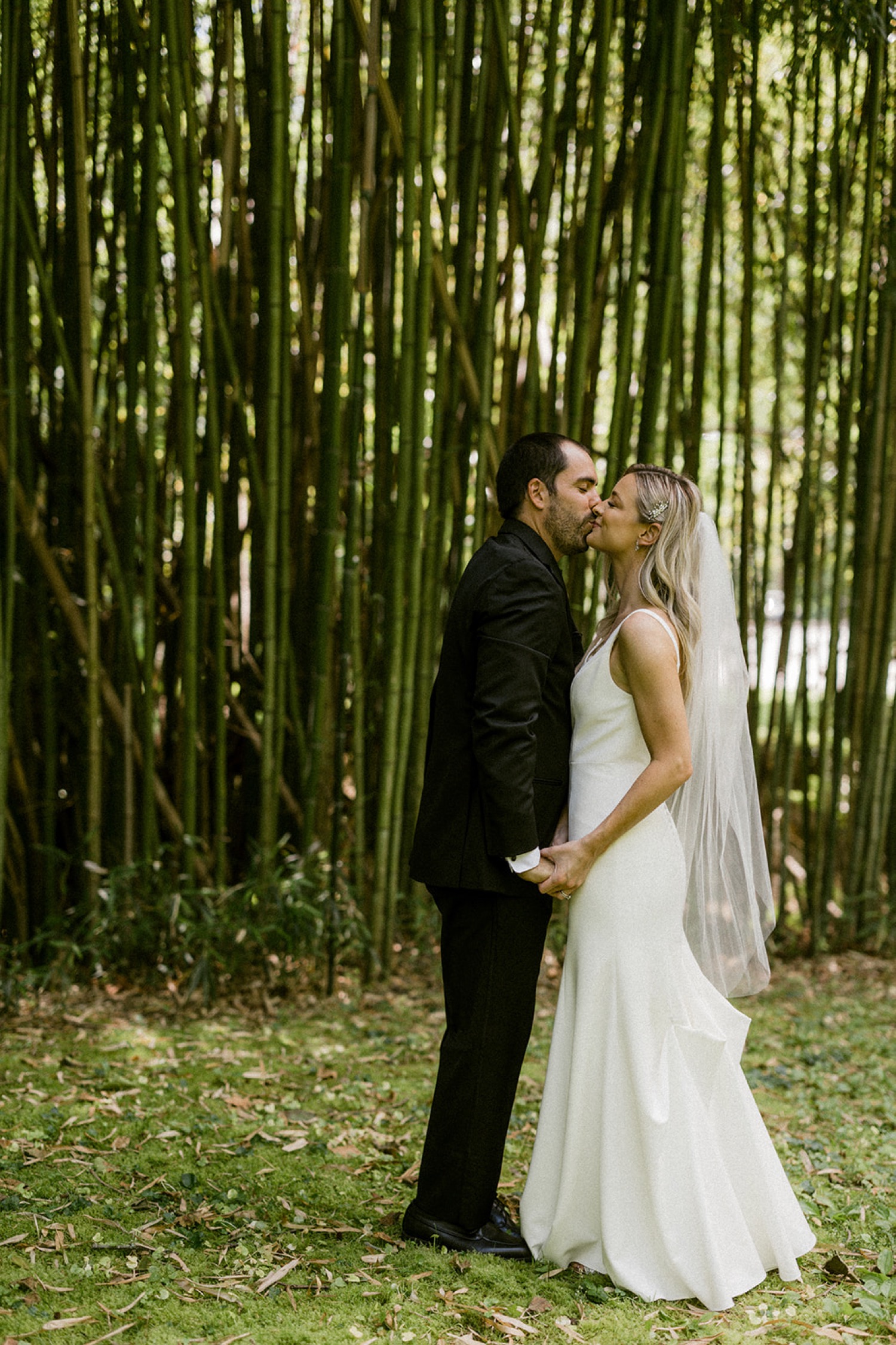 bride and groom kissing in front of bamboo the old mill wedding