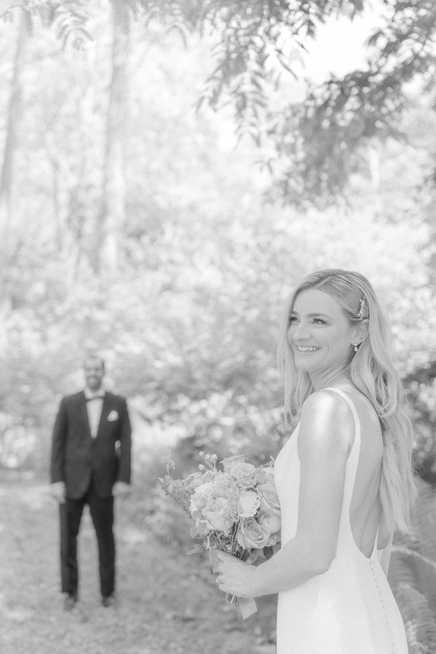 blurry out of focus bride holding flowers groom behind
