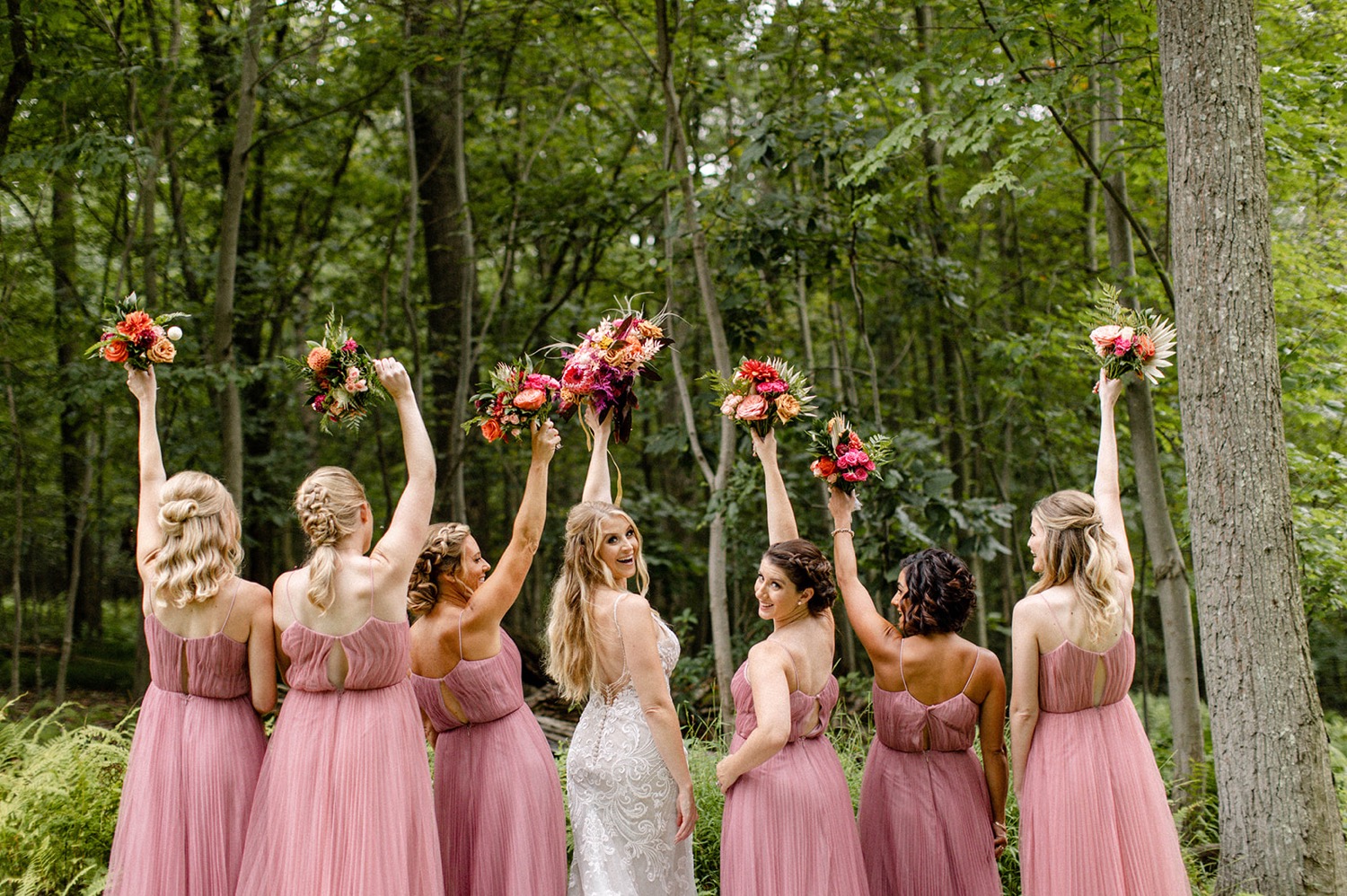 bridesmaids in pink dresses holding up flower bouquets