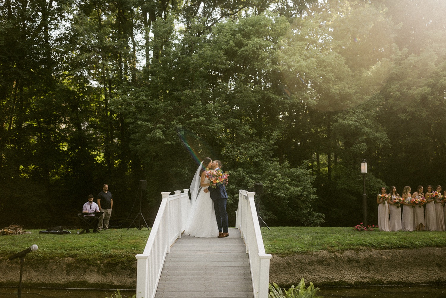 bride and groom kissing on bridge dreamy backyard wedding