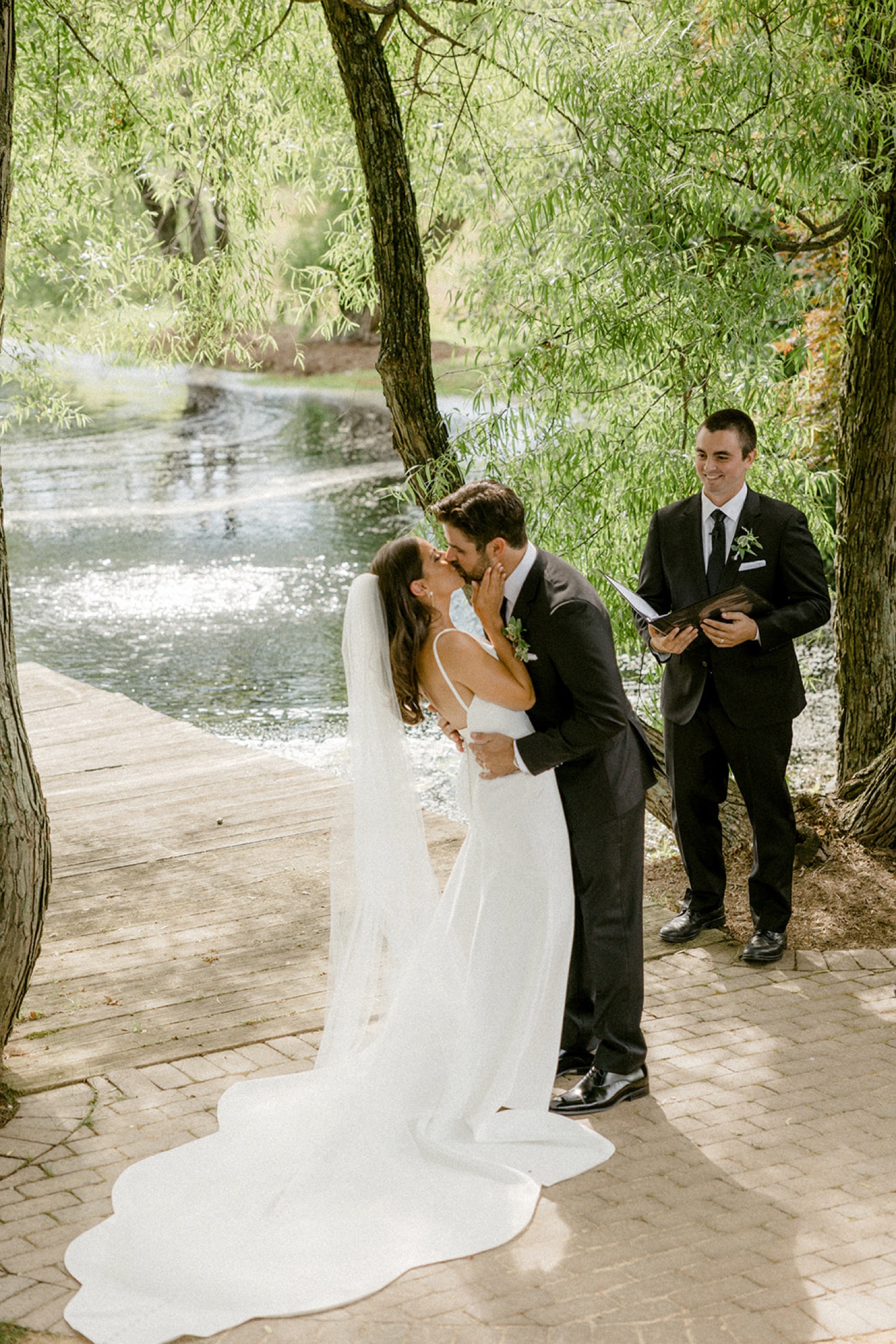bride and groom kissing in front of lake wedding ceremony the farm at eagles ridge