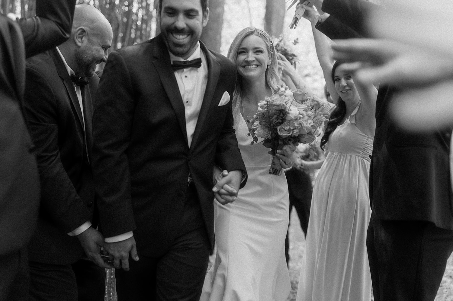 bride and groom smiling running through arms