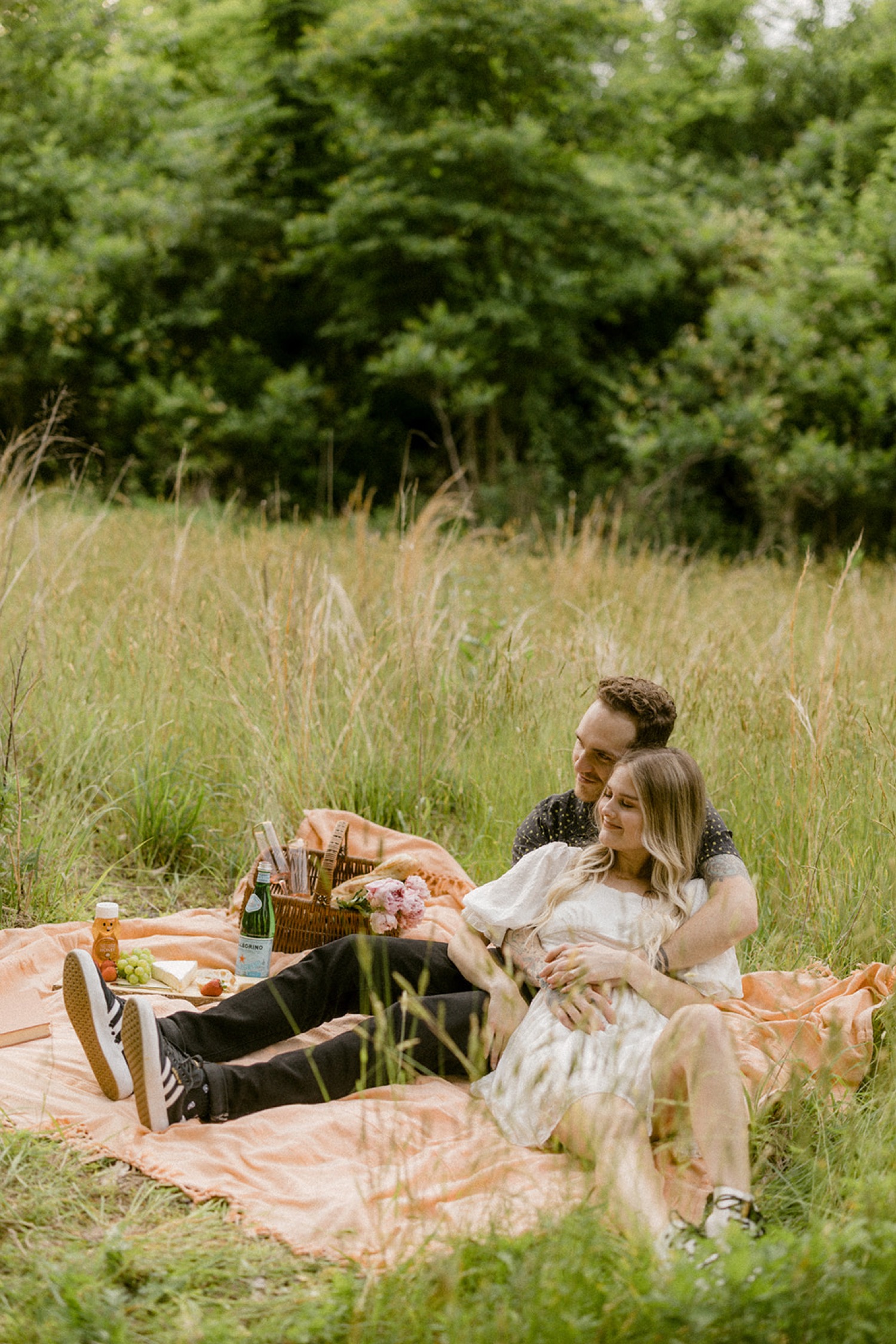 couple lounging on picnic blanket in field bohemian engagement session