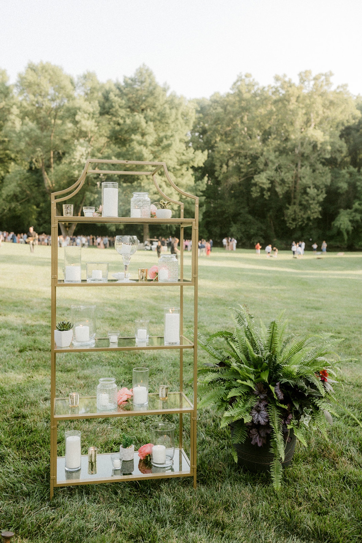 candles on gold shelves with fern wedding reception entrance