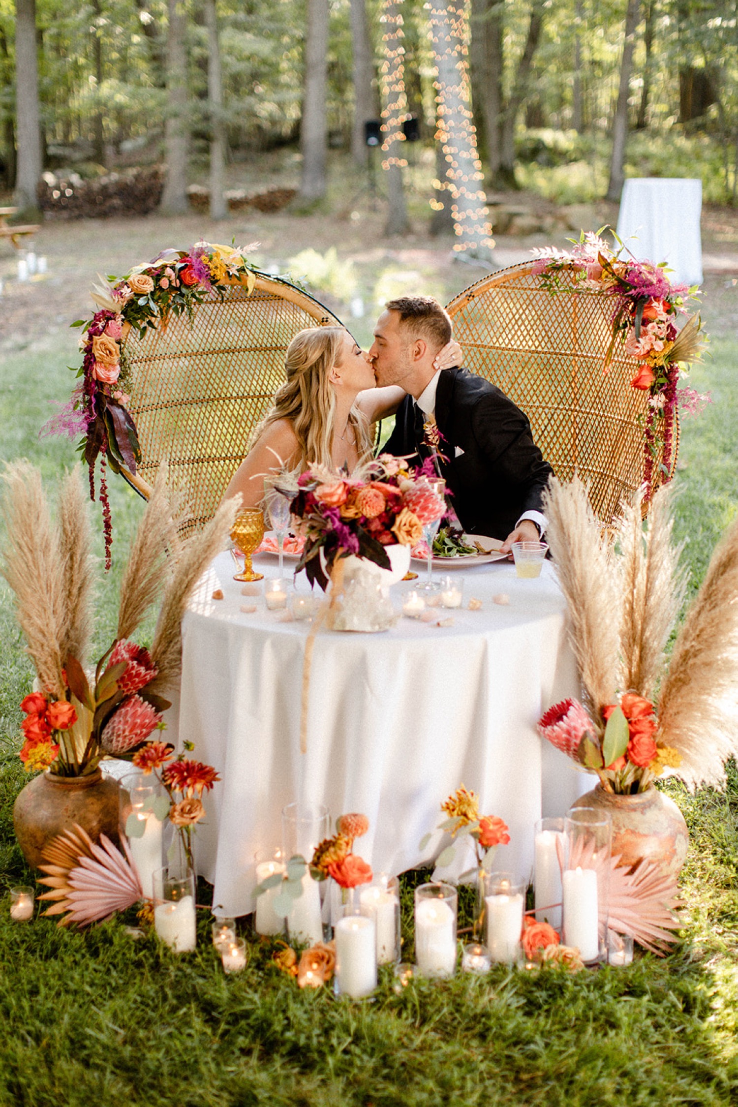 bride and groom kissing at head table in peacock chairs colorful bohemian backyard wedding