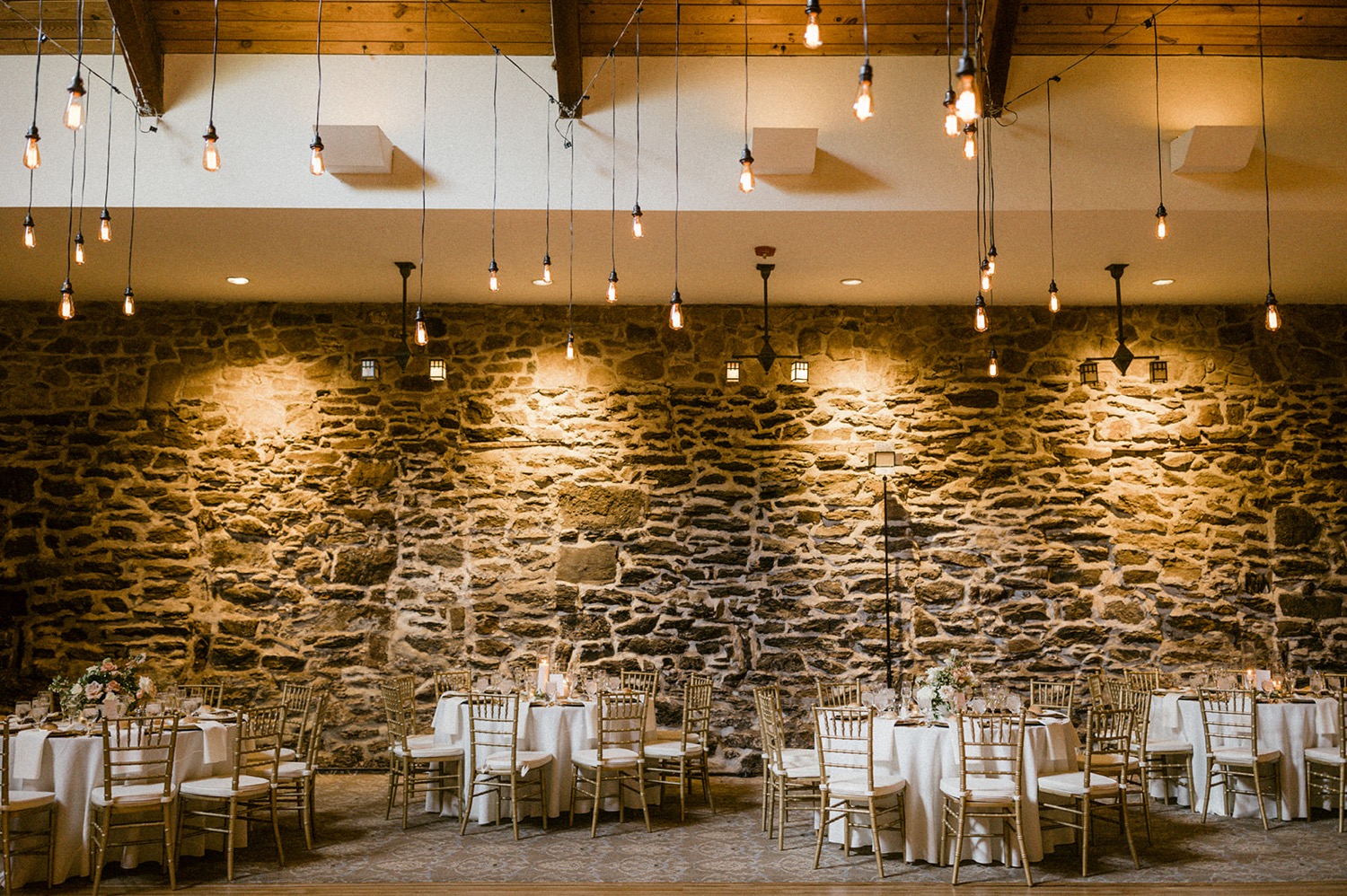 the old mill philadelphia wedding reception stone wall table chairs hanging lights