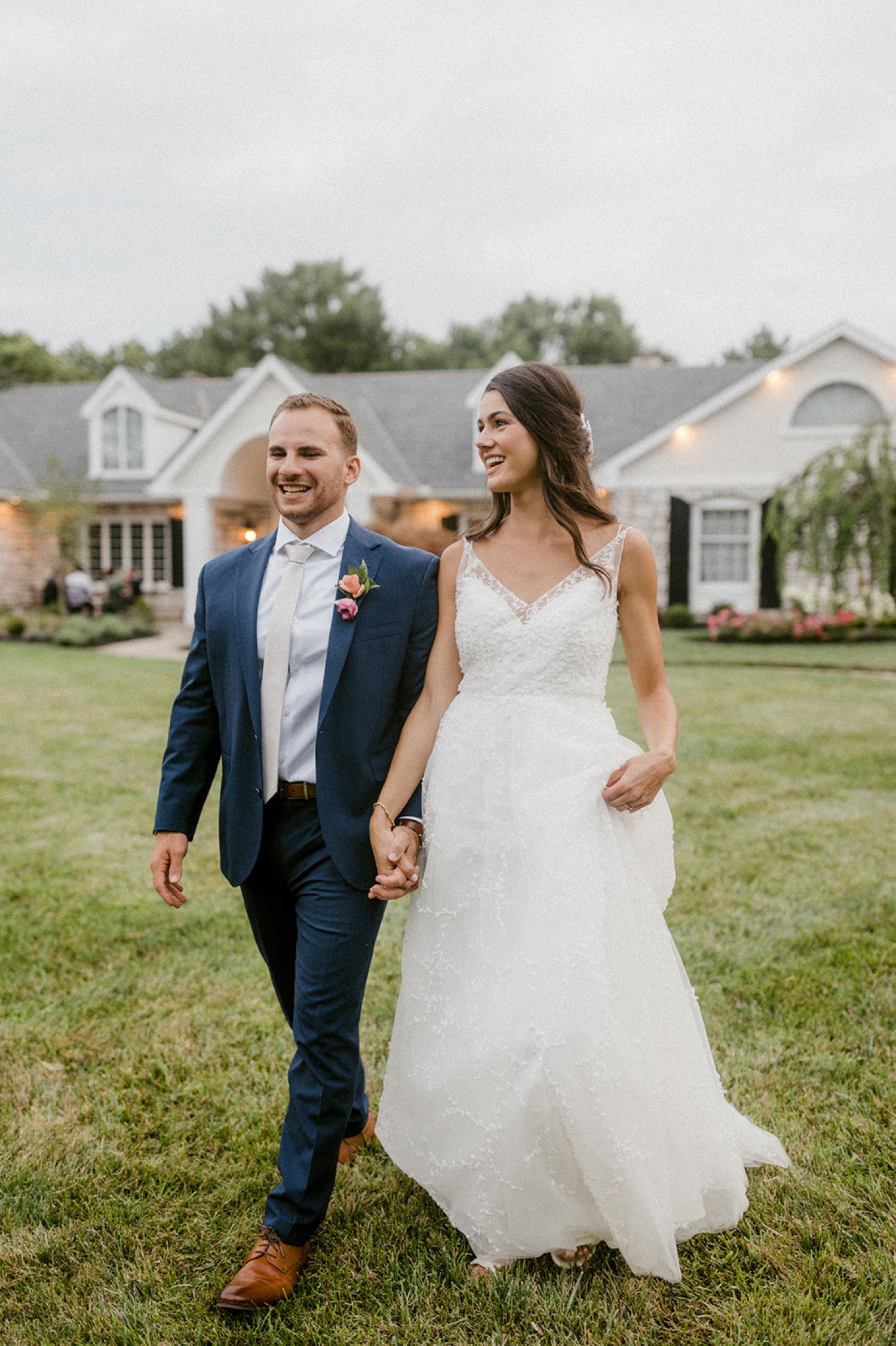 bride and groom holding hands walking through grass dreamy backyard wedding