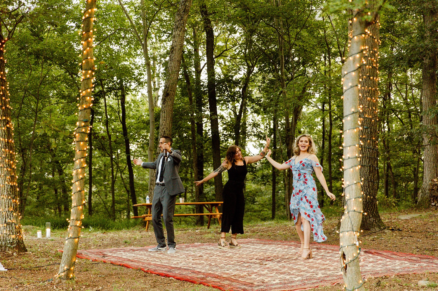 guests dancing on carpet dance floor in forest bohemian backyard wedding
