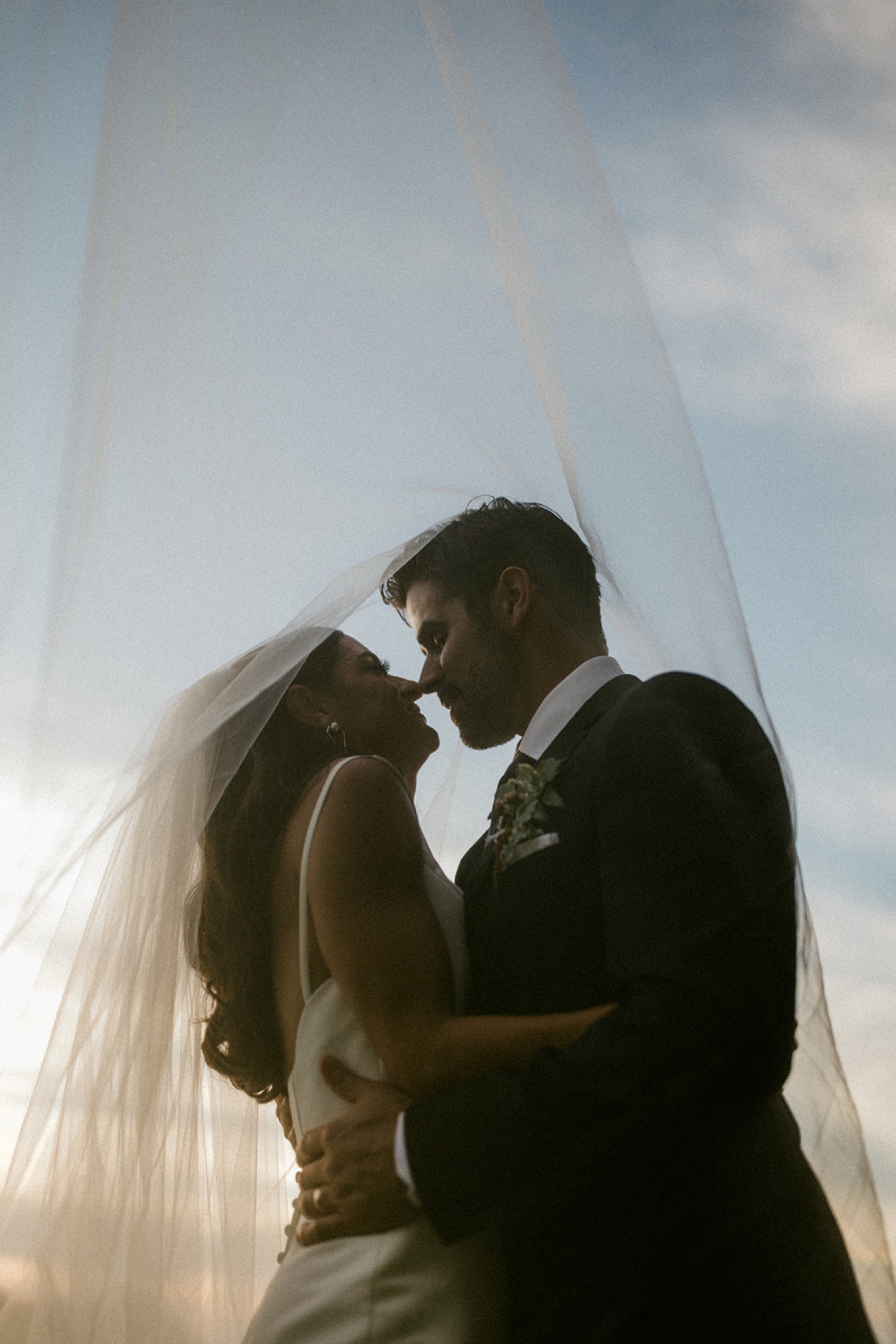 couple kissing under wedding veil