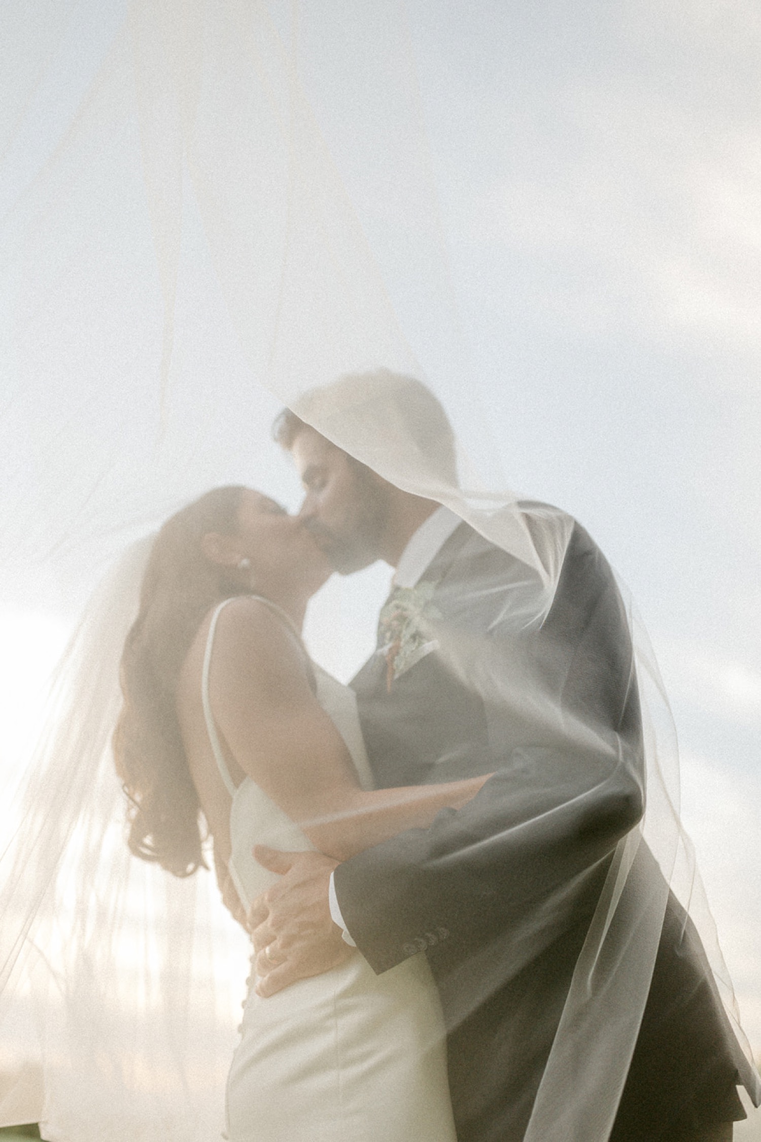 couple kissing under bridal veil