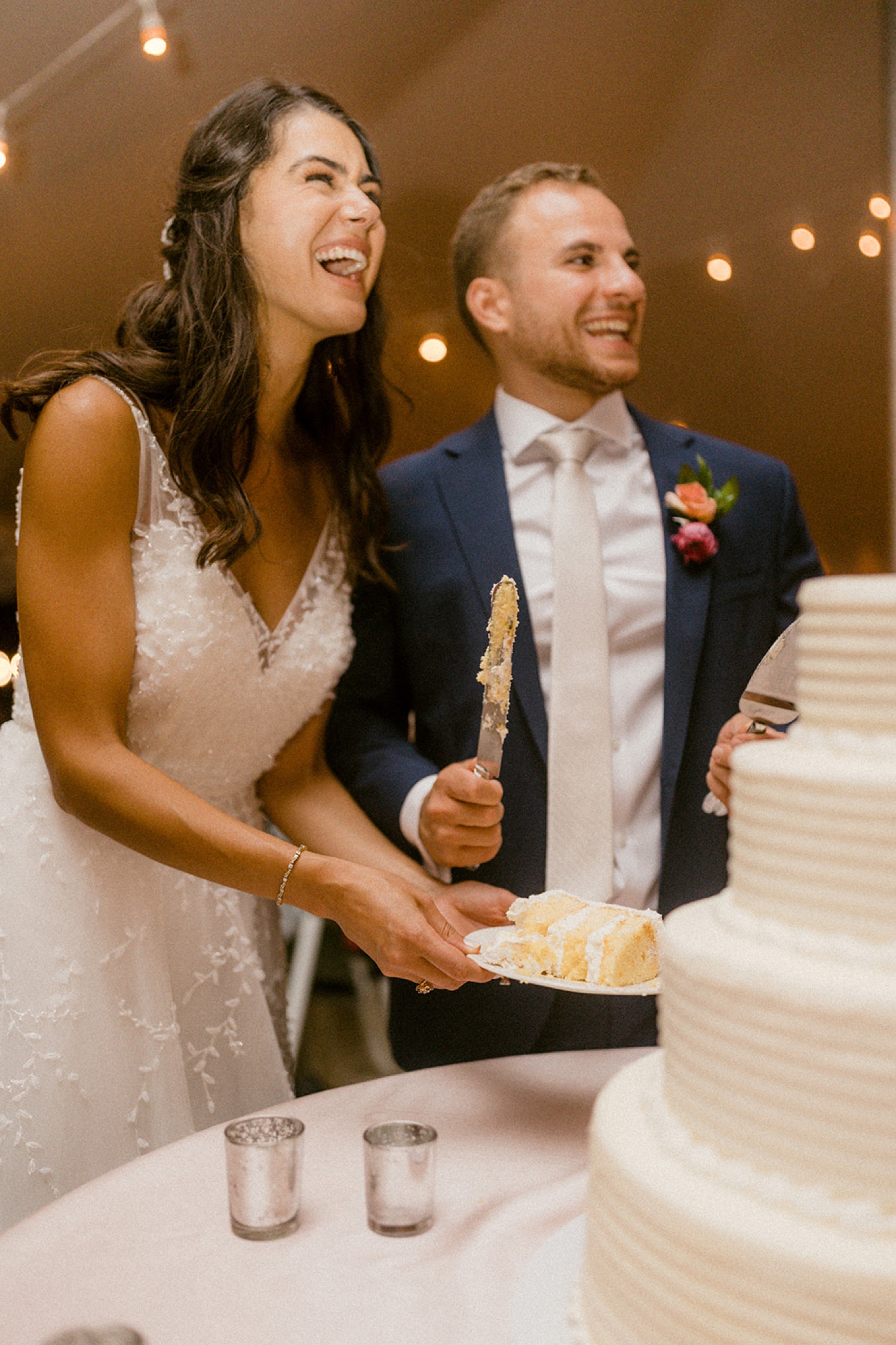 bride and groom laughing serving wedding cake