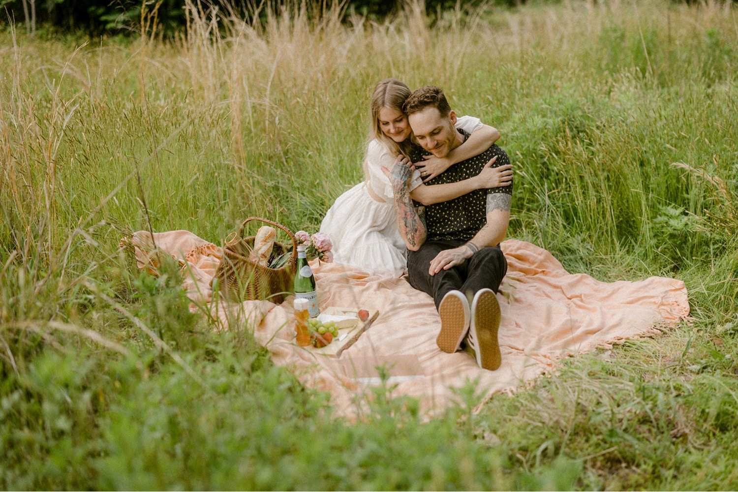 couple sitting on picnic blanket in field