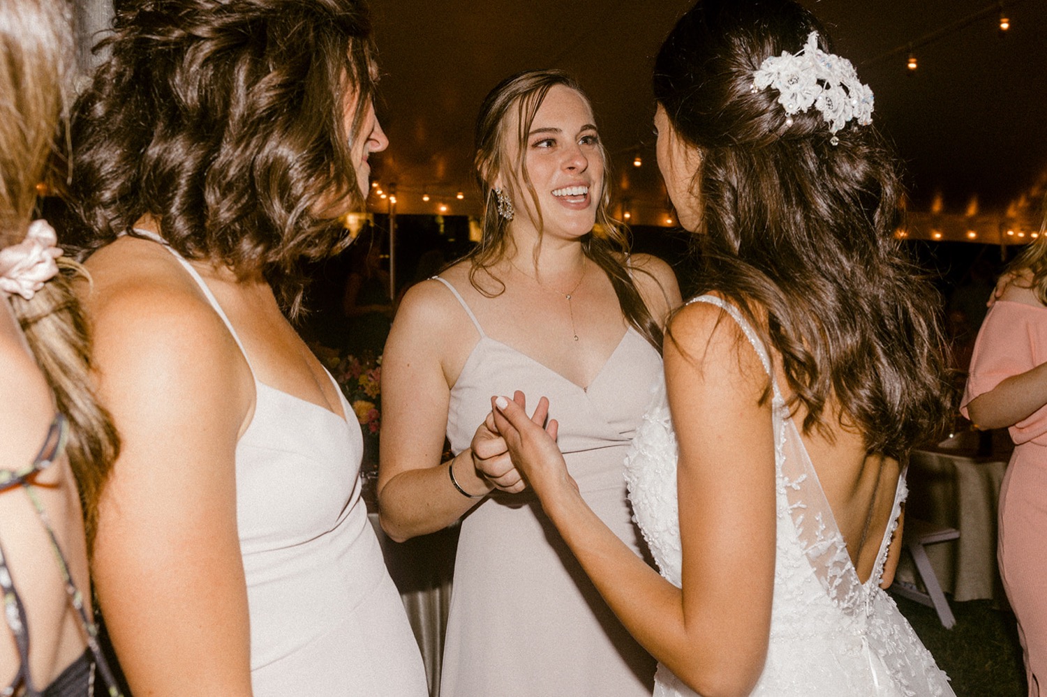 bride talking to bridesmaid holding hands at wedding reception