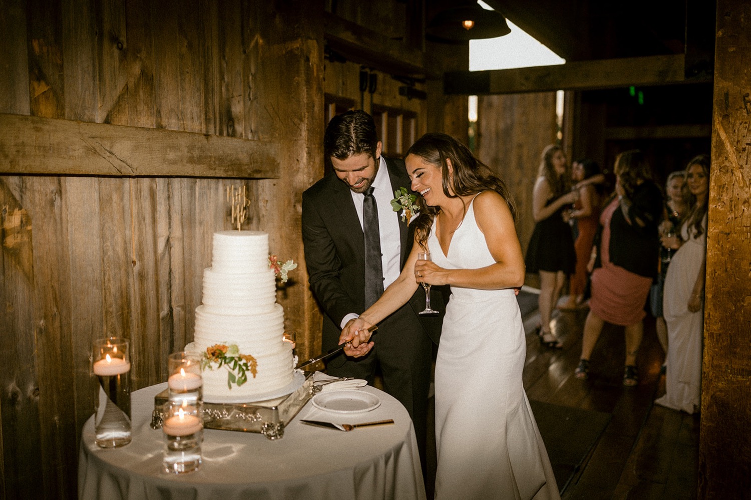 couple cutting wedding cake barn