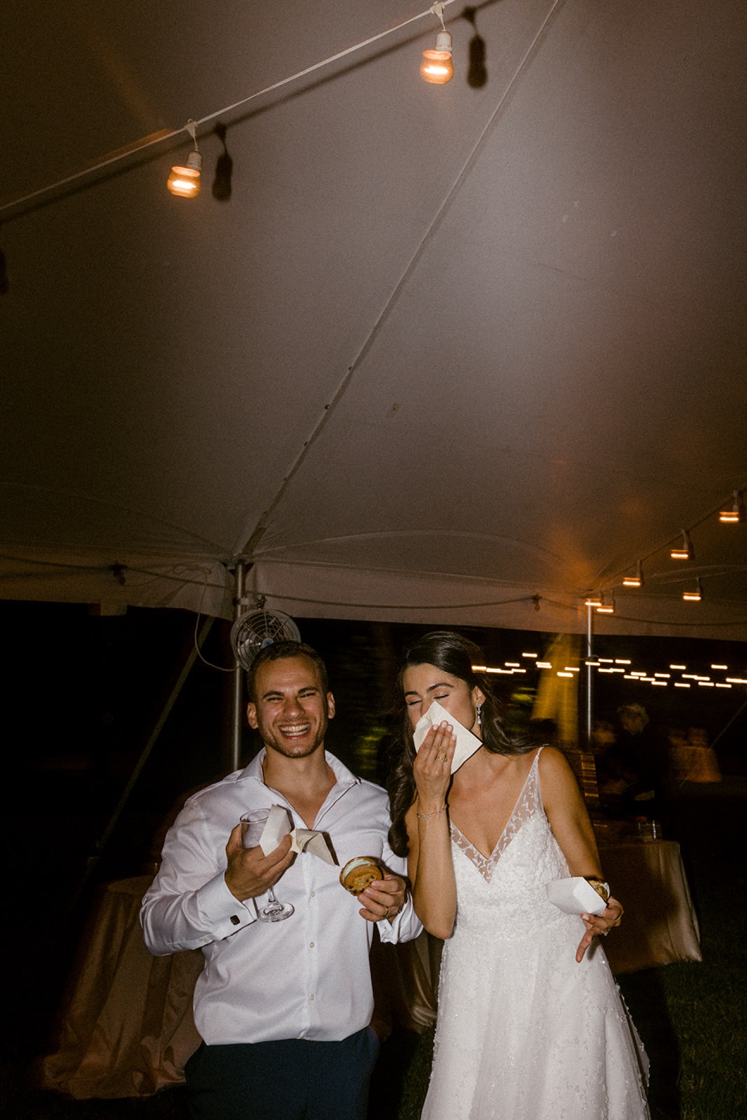 bride and groom eating ice cream cookie sandwiches wedding reception