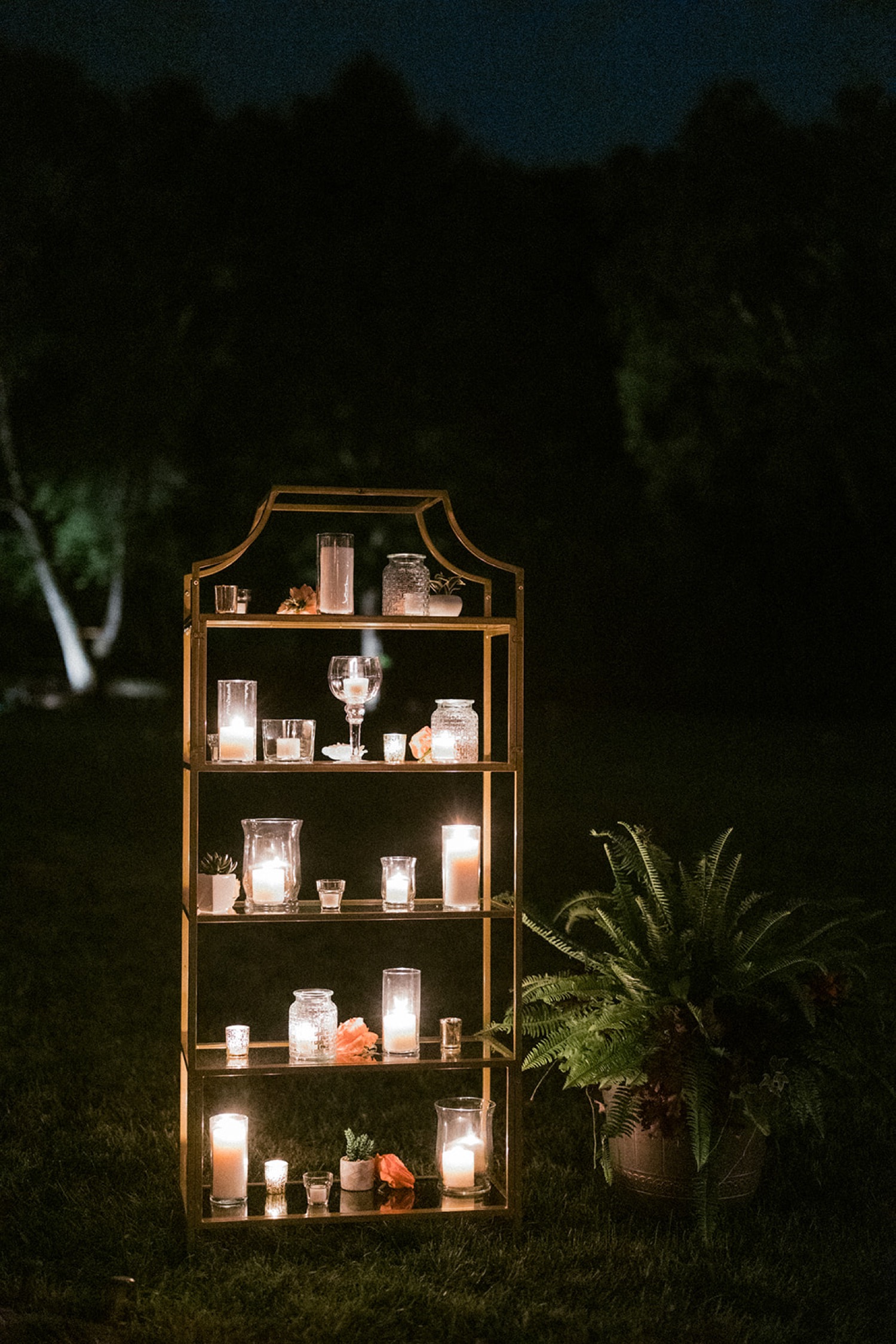candles on gold shelf glowing at night in the dark dreamy backyard wedding