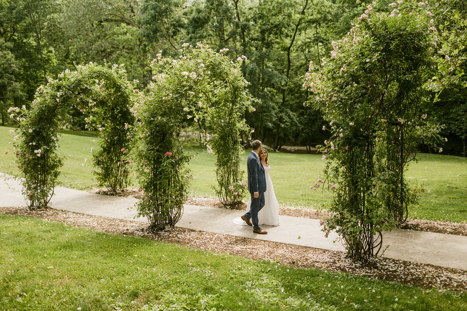 couple walking under rose arch walkway moonstone manor wedding session