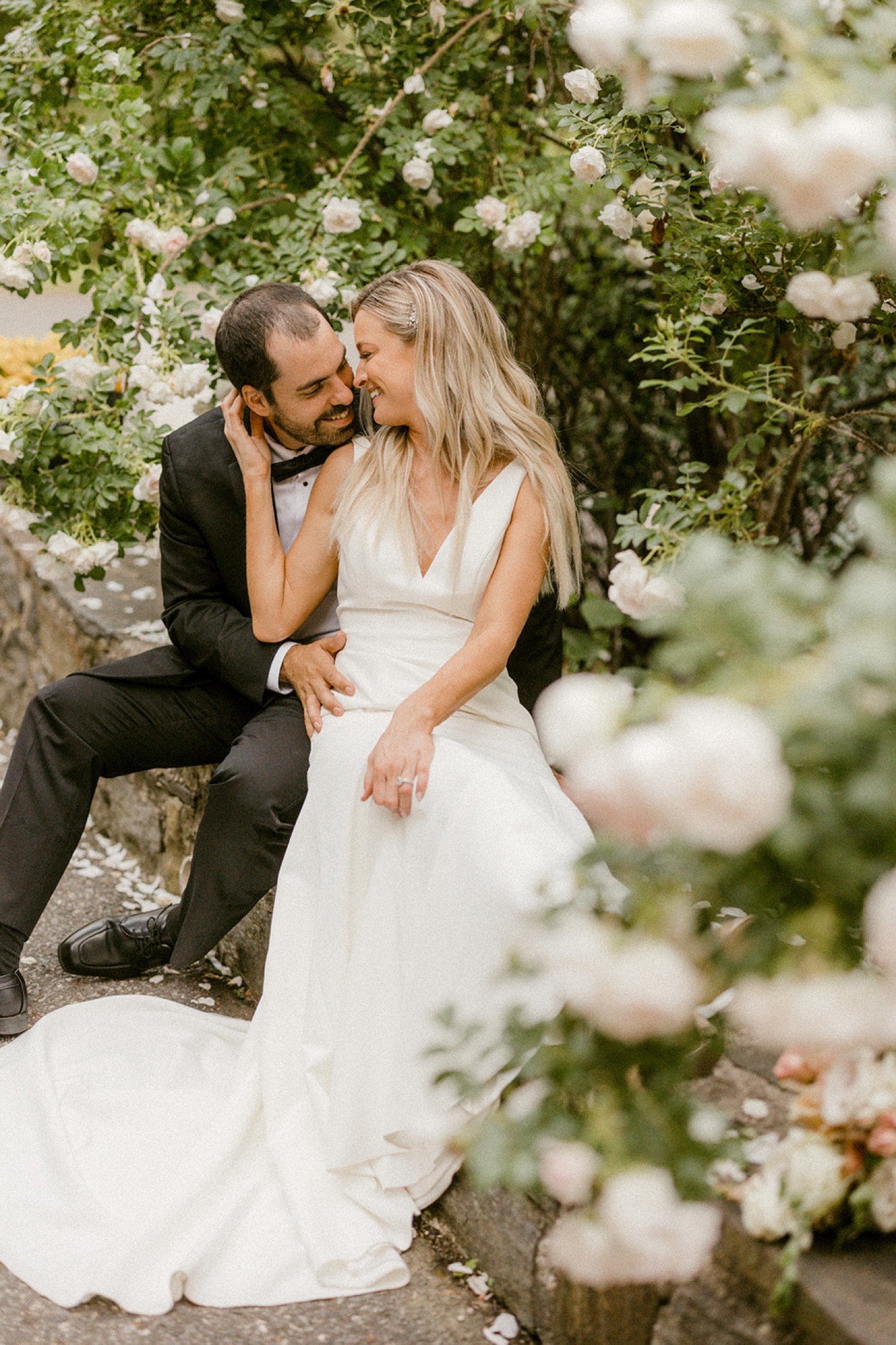 couple kissing intimate moment in rose garden wedding