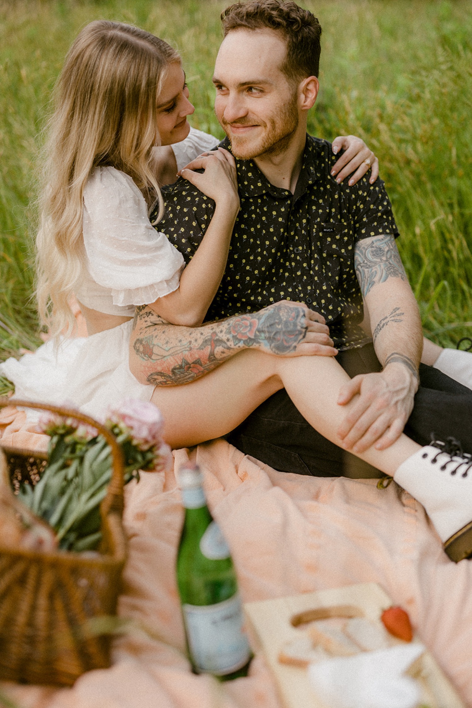 couple sitting on picnic blanket whimsical field engagement session