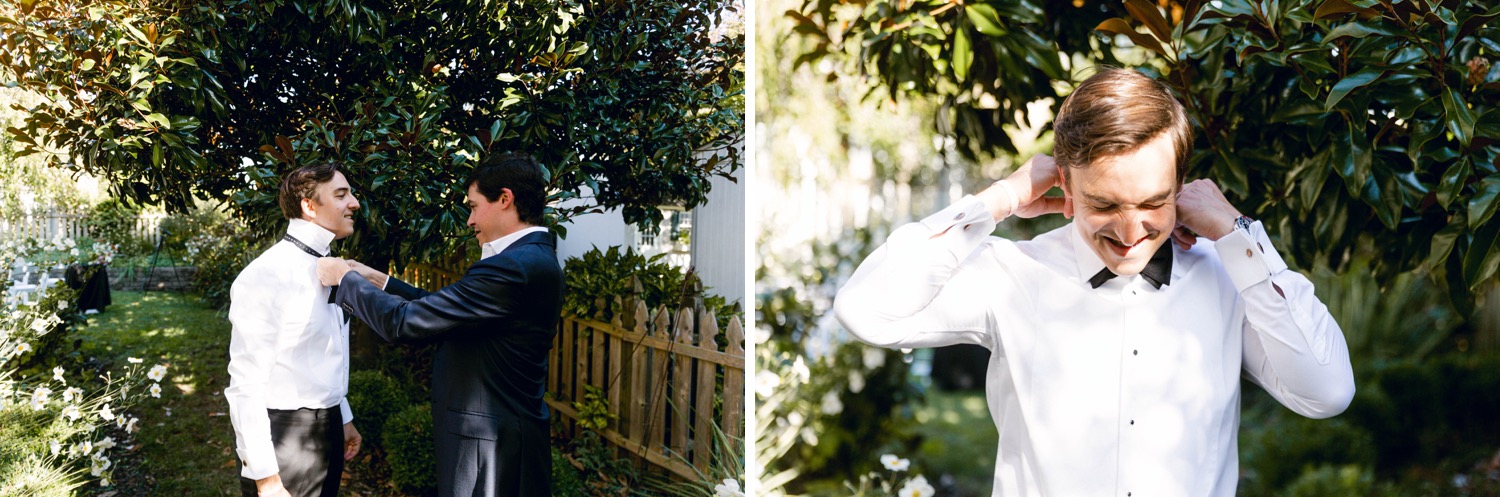 groom putting on bowtie in backyard