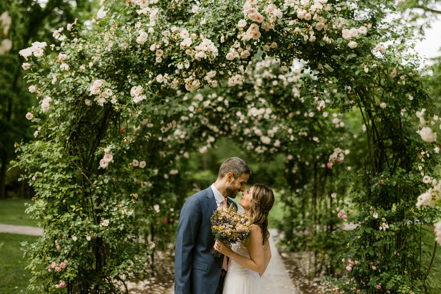 couple embracing kissing under rose arches moonstone manor wedding session