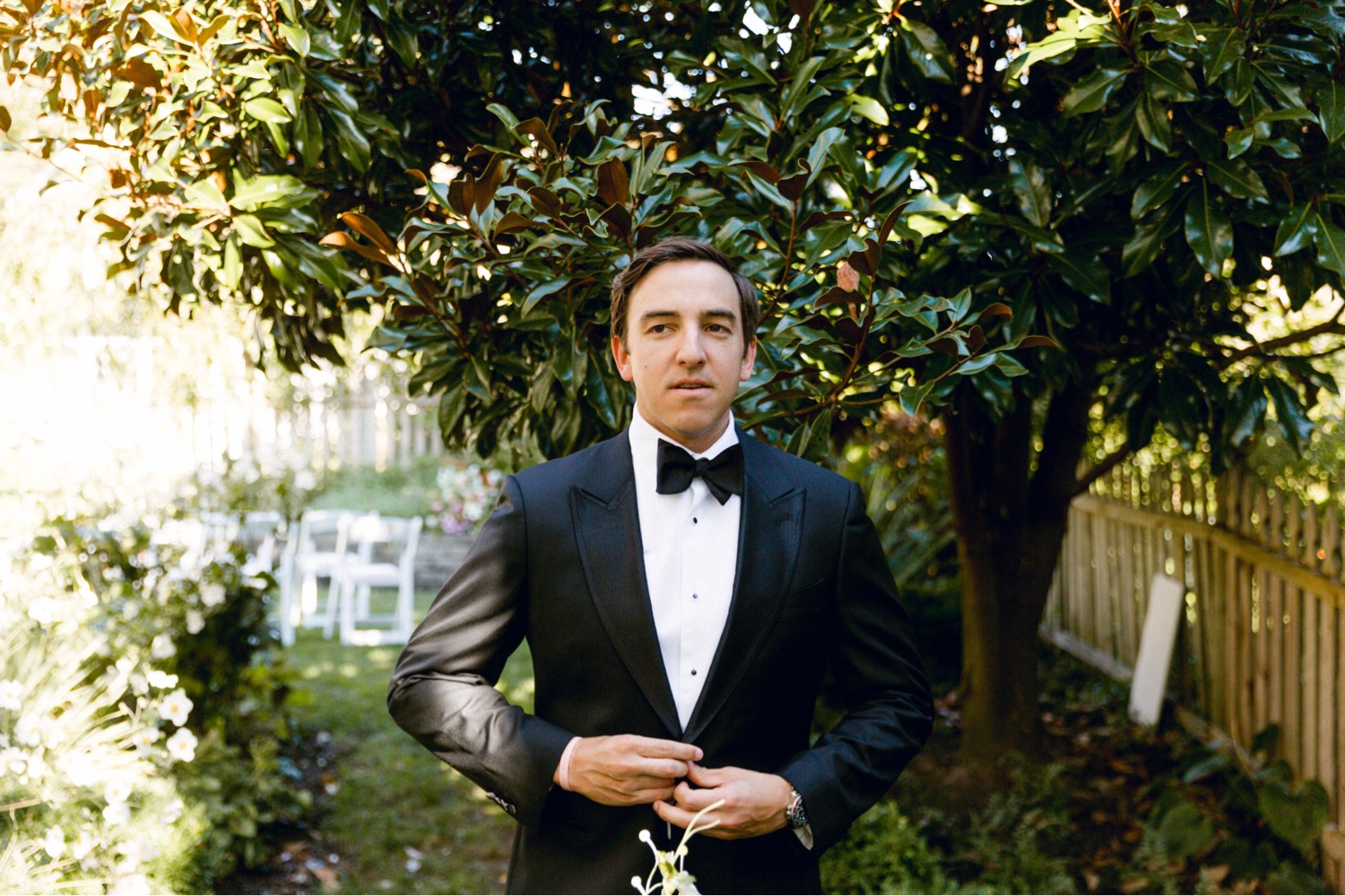 groom buttoning suit jacket luxurious backyard wedding