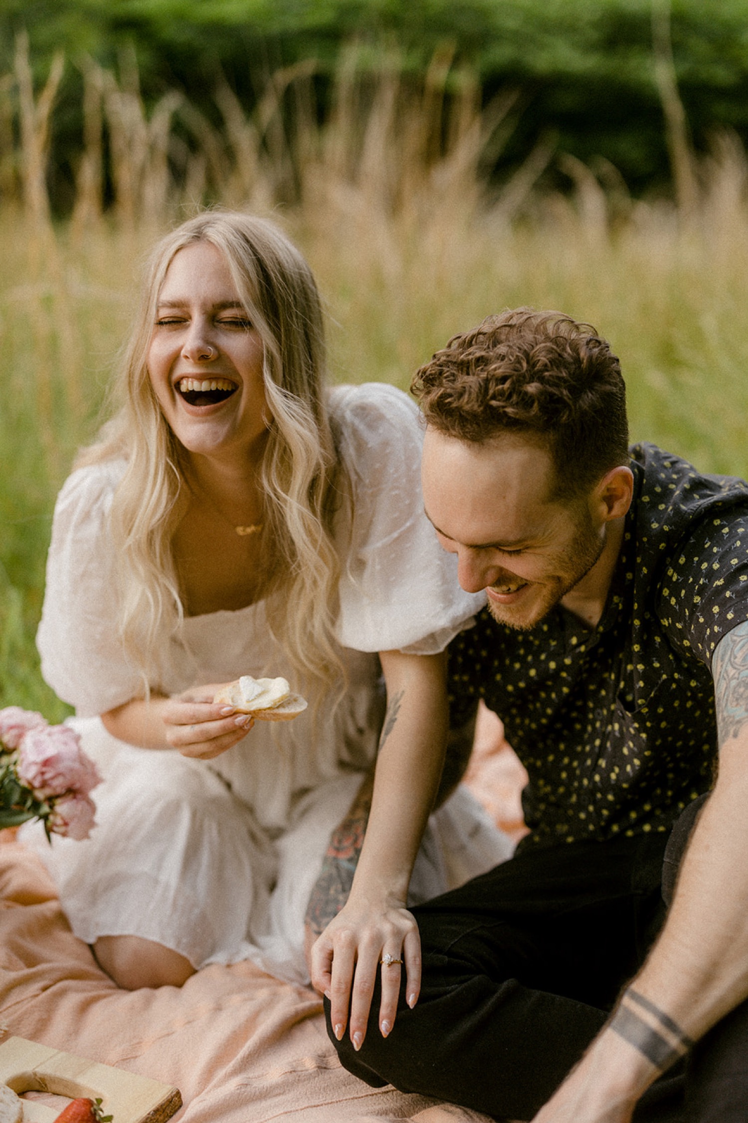 couple laughing eating picnic in field