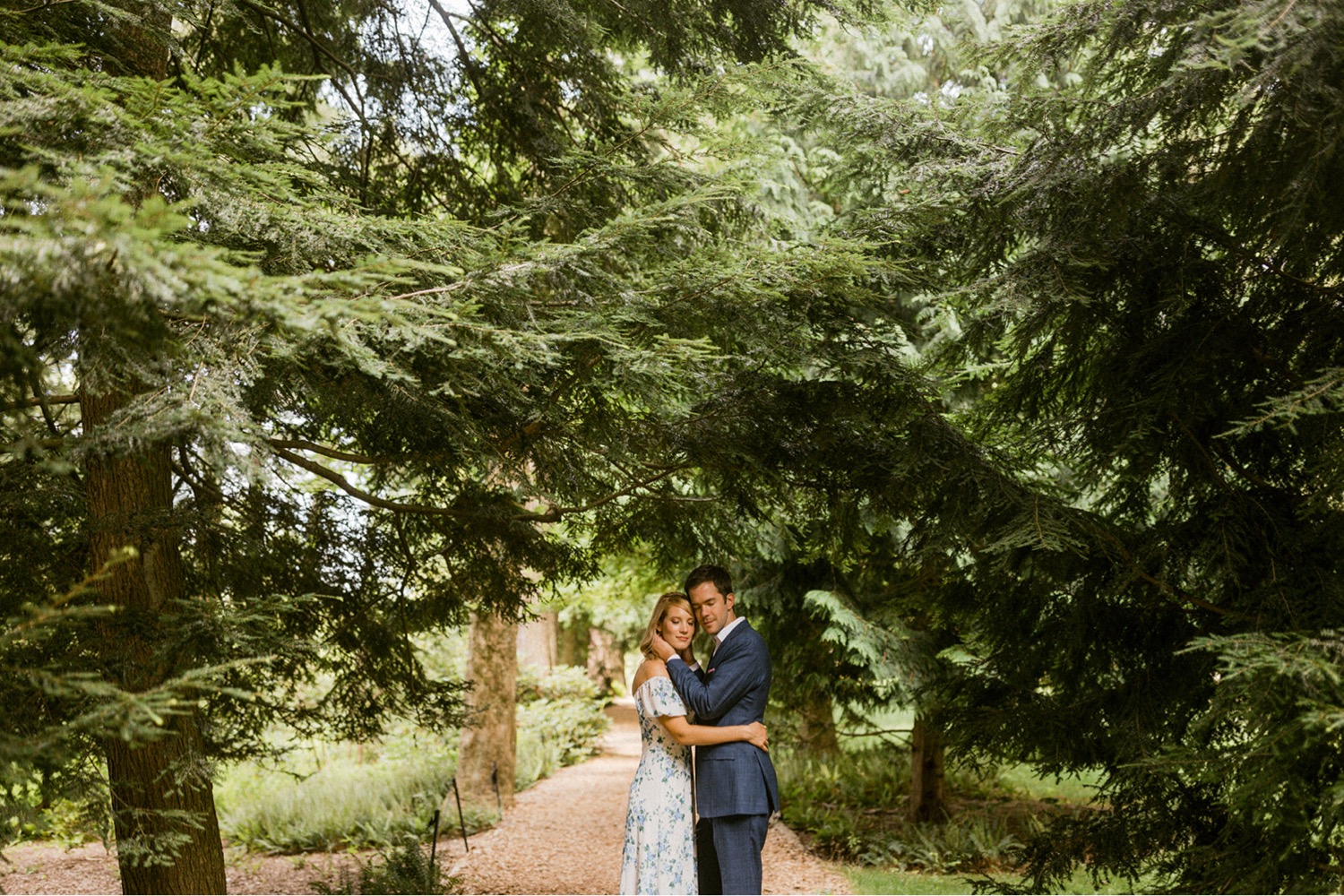 couple embracing under greenery foliage in longwood gardens