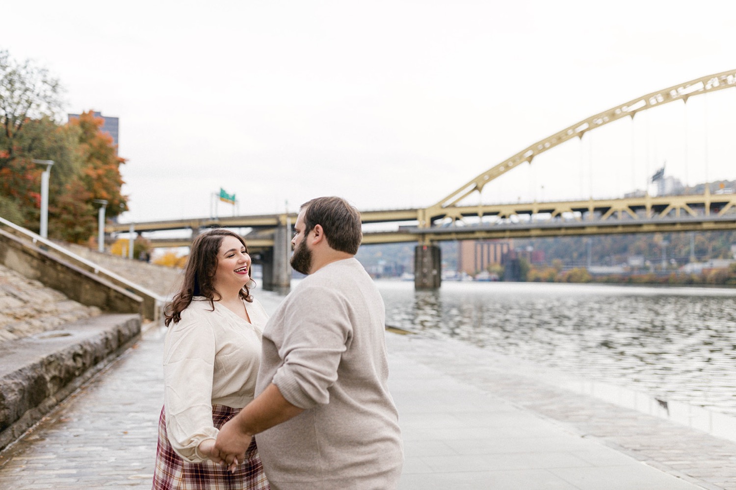 couple in front of water and bridge