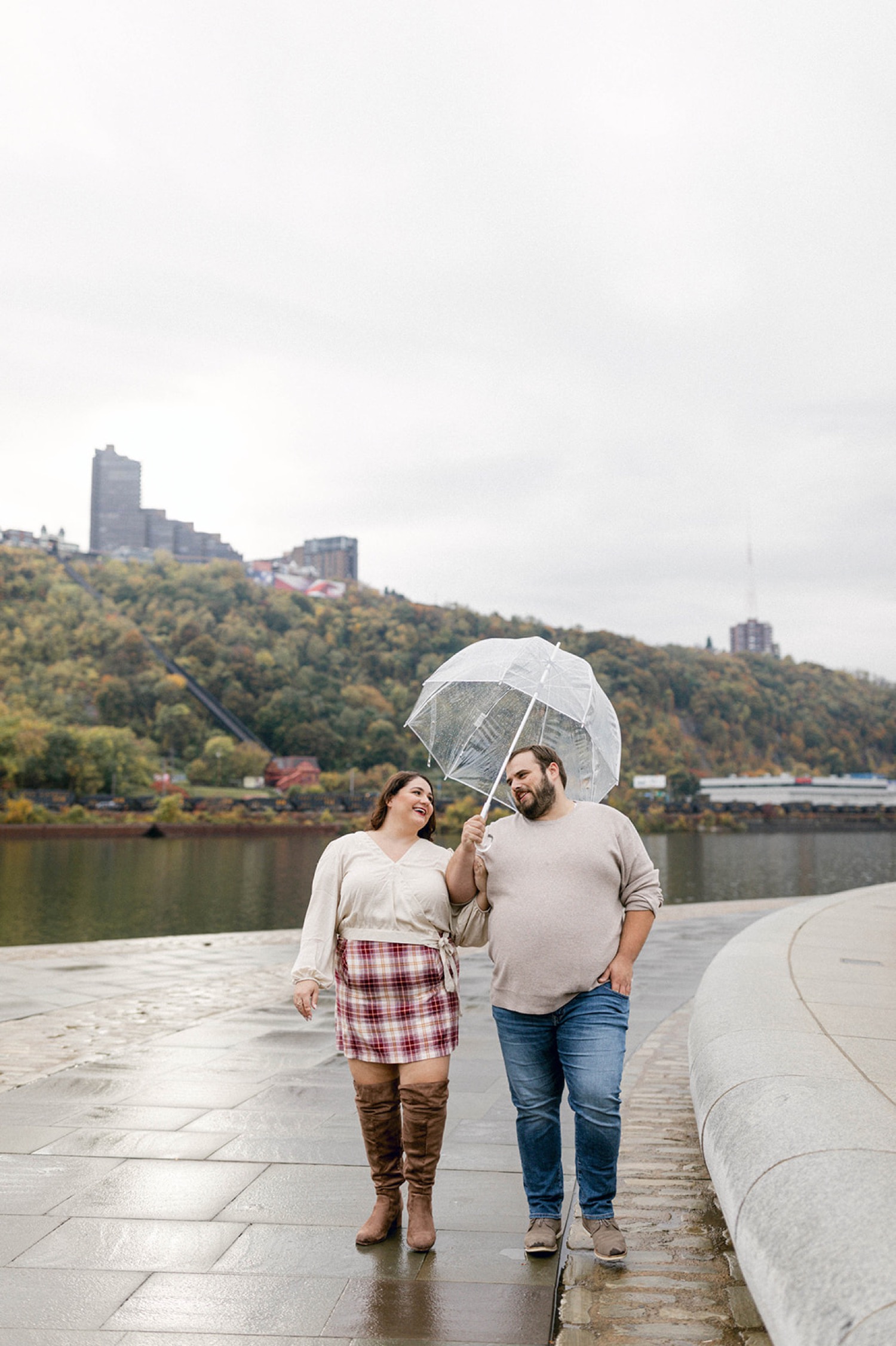 couple walking with clear umbrella engagement session