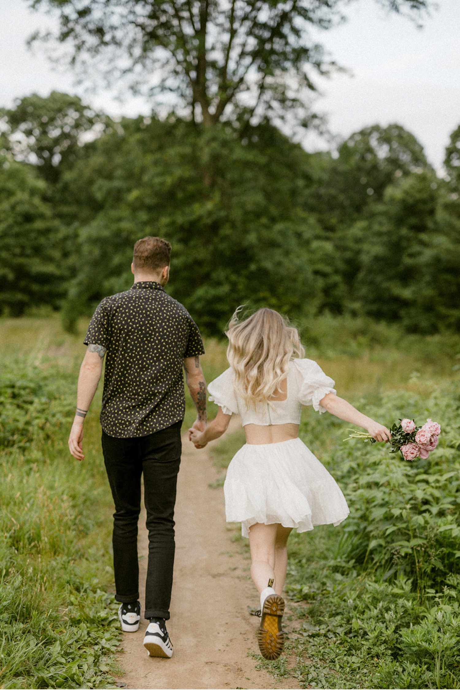 couple holding hands running on trail bohemian engagement session