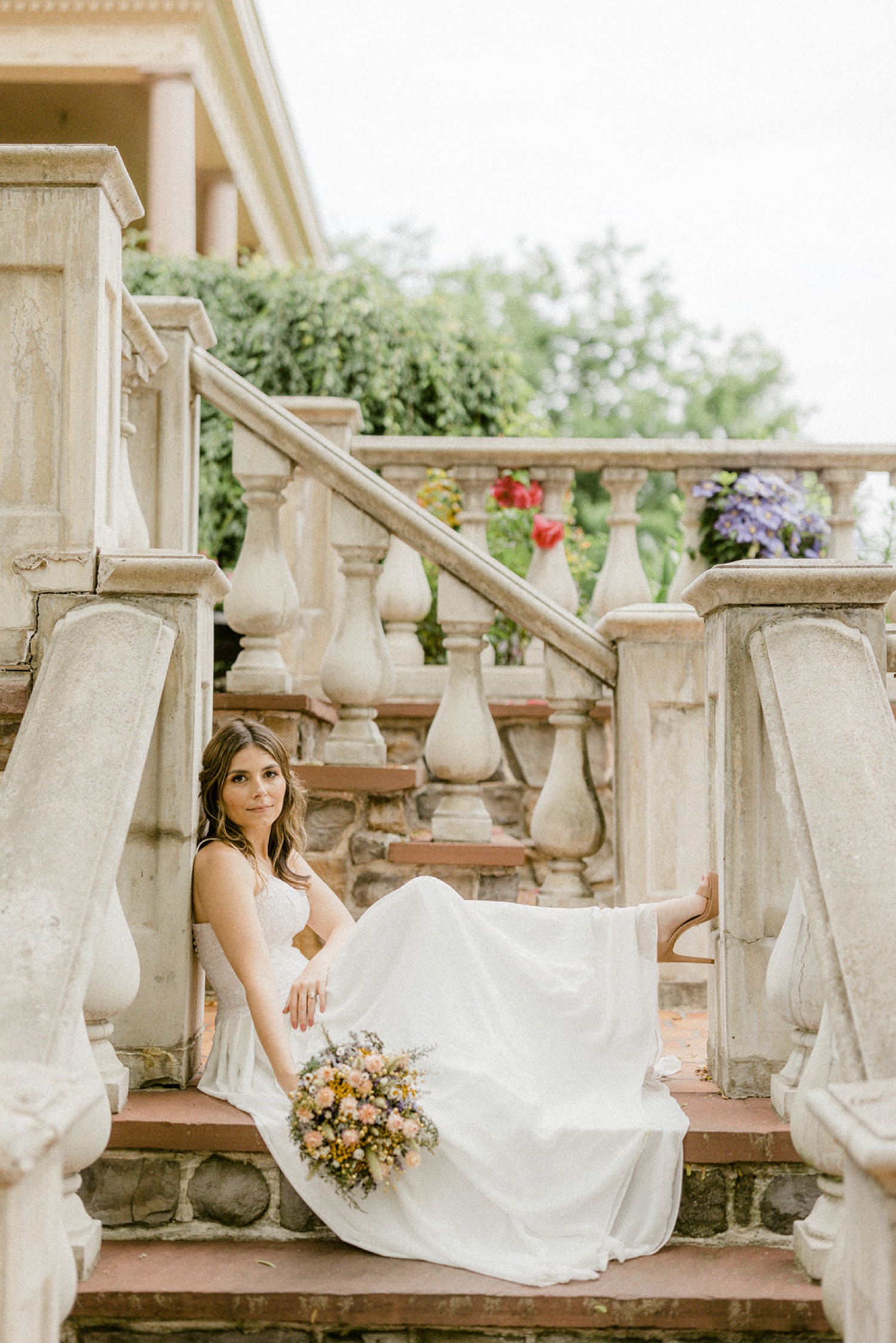 bride sitting on steps holding bouquet whimsical moonstone manor wedding