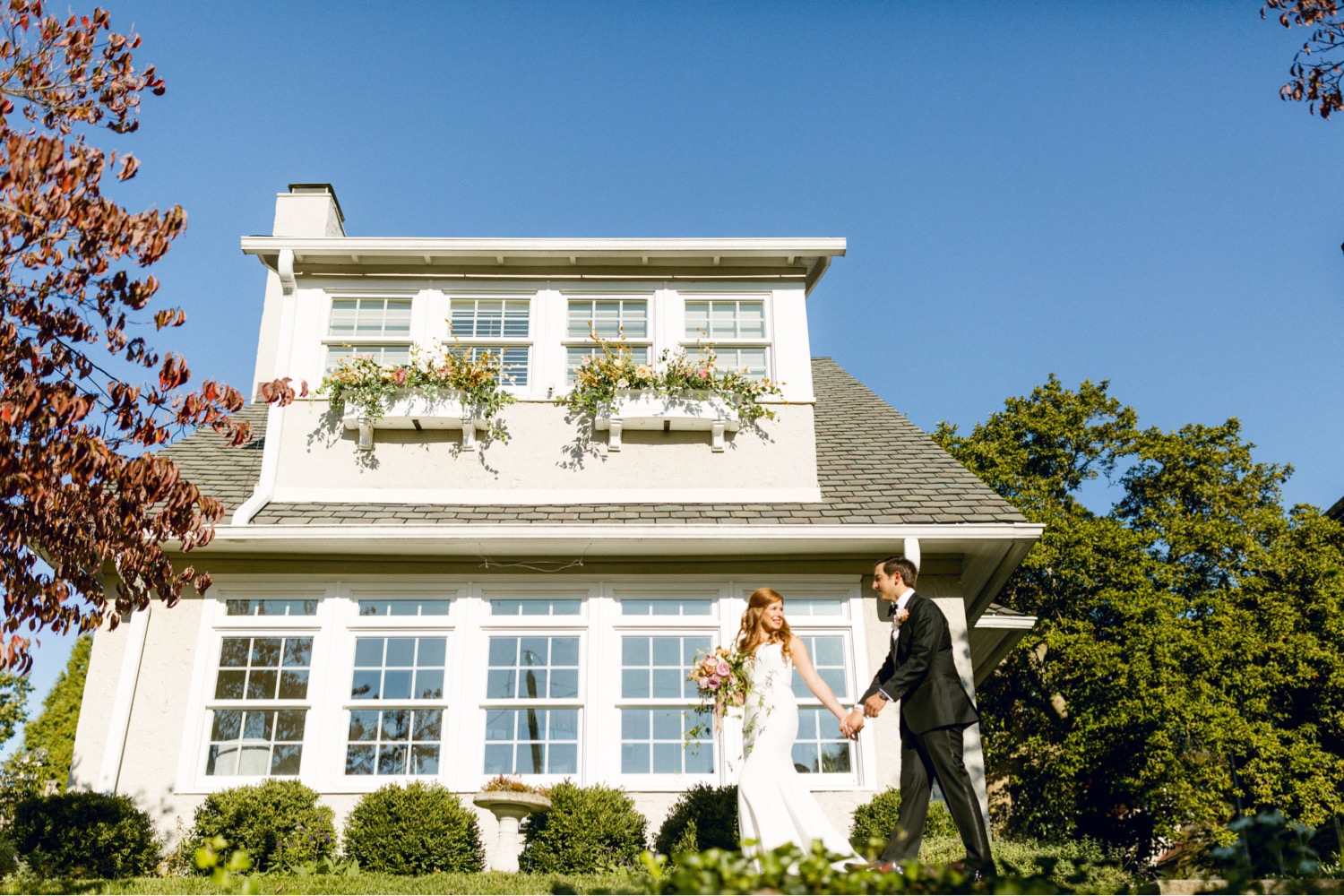 bride and groom in front of house luxurious main line backyard wedding